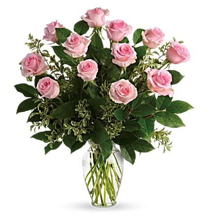 Arrangement of light pink roses with lush foliage in a clear glass vase