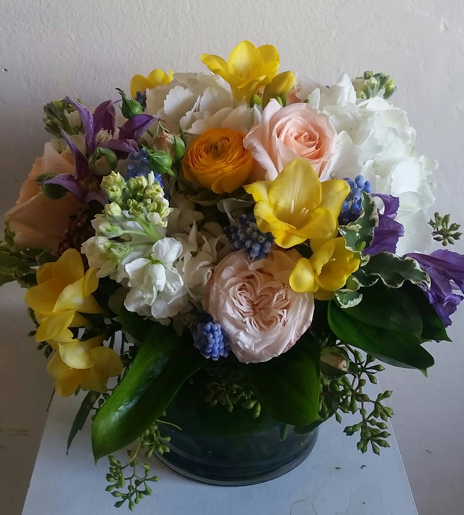 Mixed bouquet of yellow, white, pink, and purple flowers in a dark vase