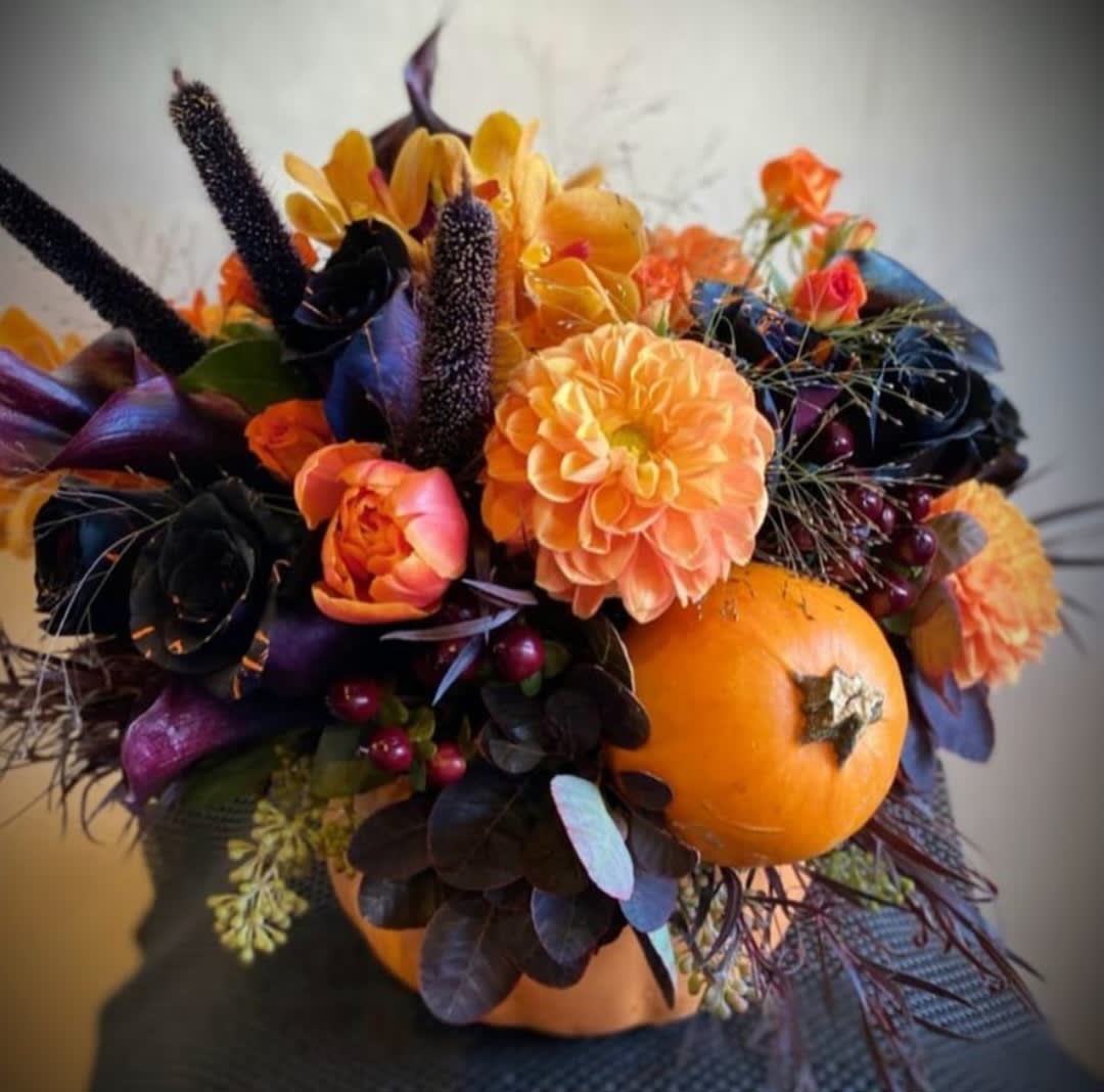 Orange and black floral arrangement with pumpkins and autumn blooms