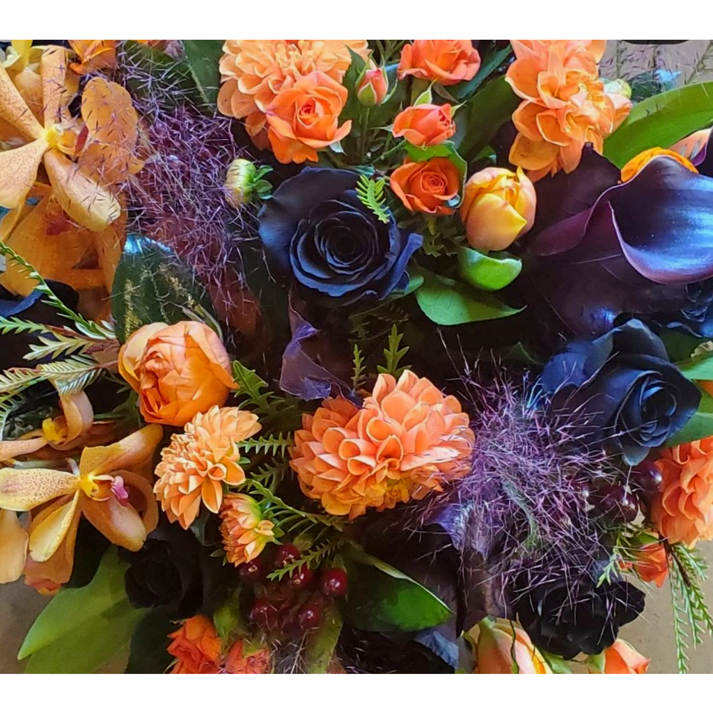 Orange and black floral arrangement with orchids and roses
