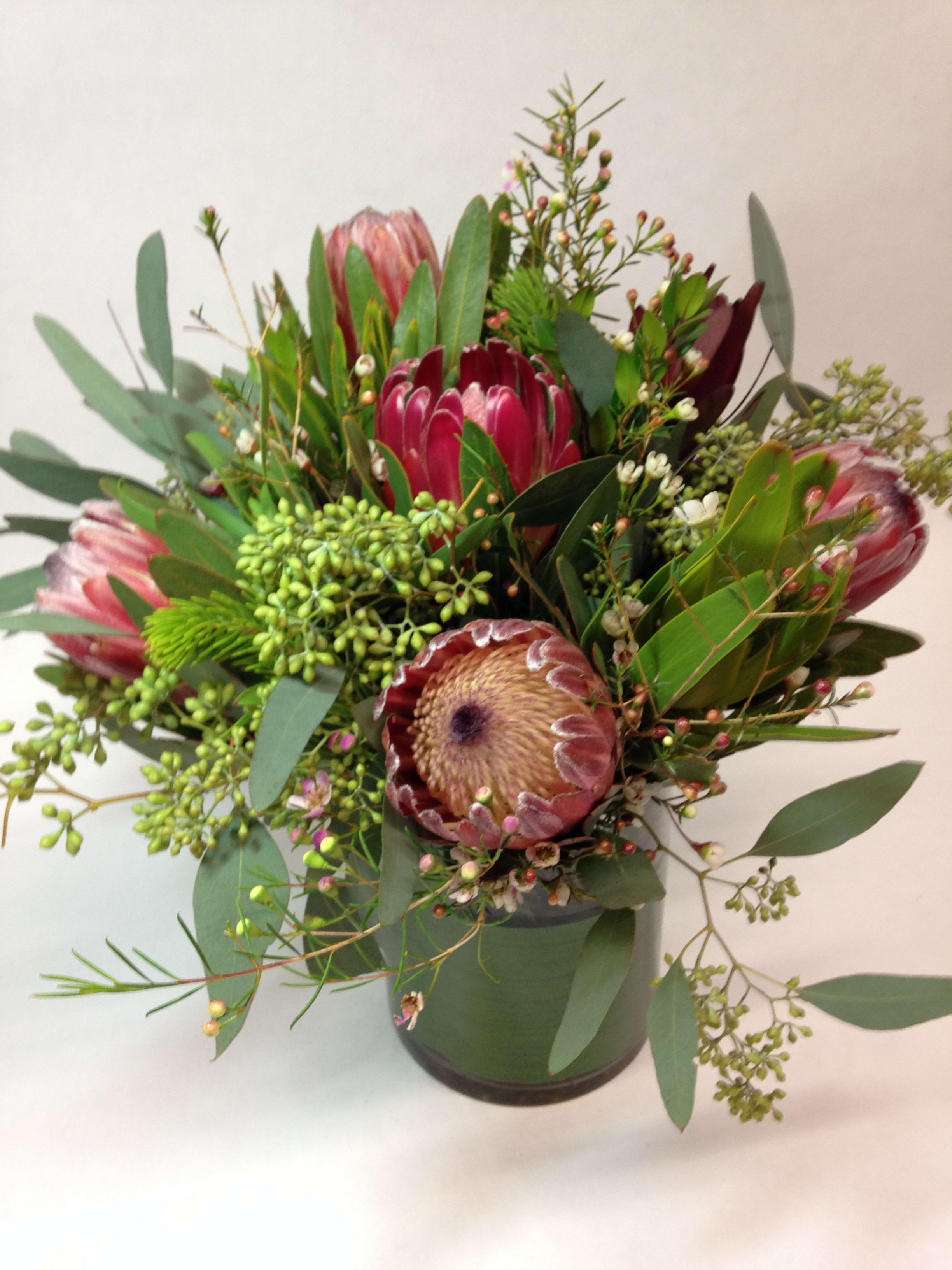 Bouquet of pink protea and greenery in a dark vase
