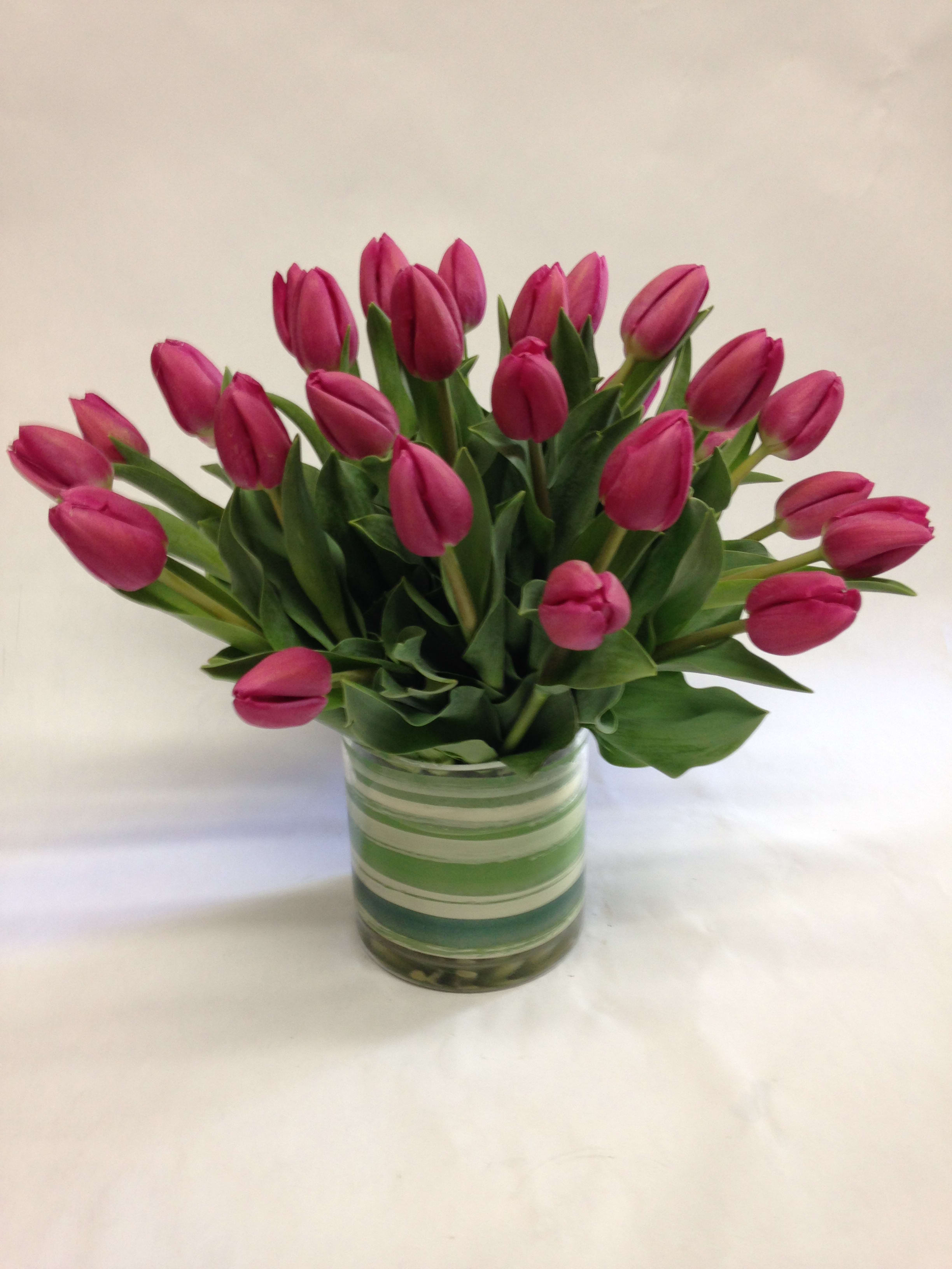 Pink tulips arranged in a striped glass vase