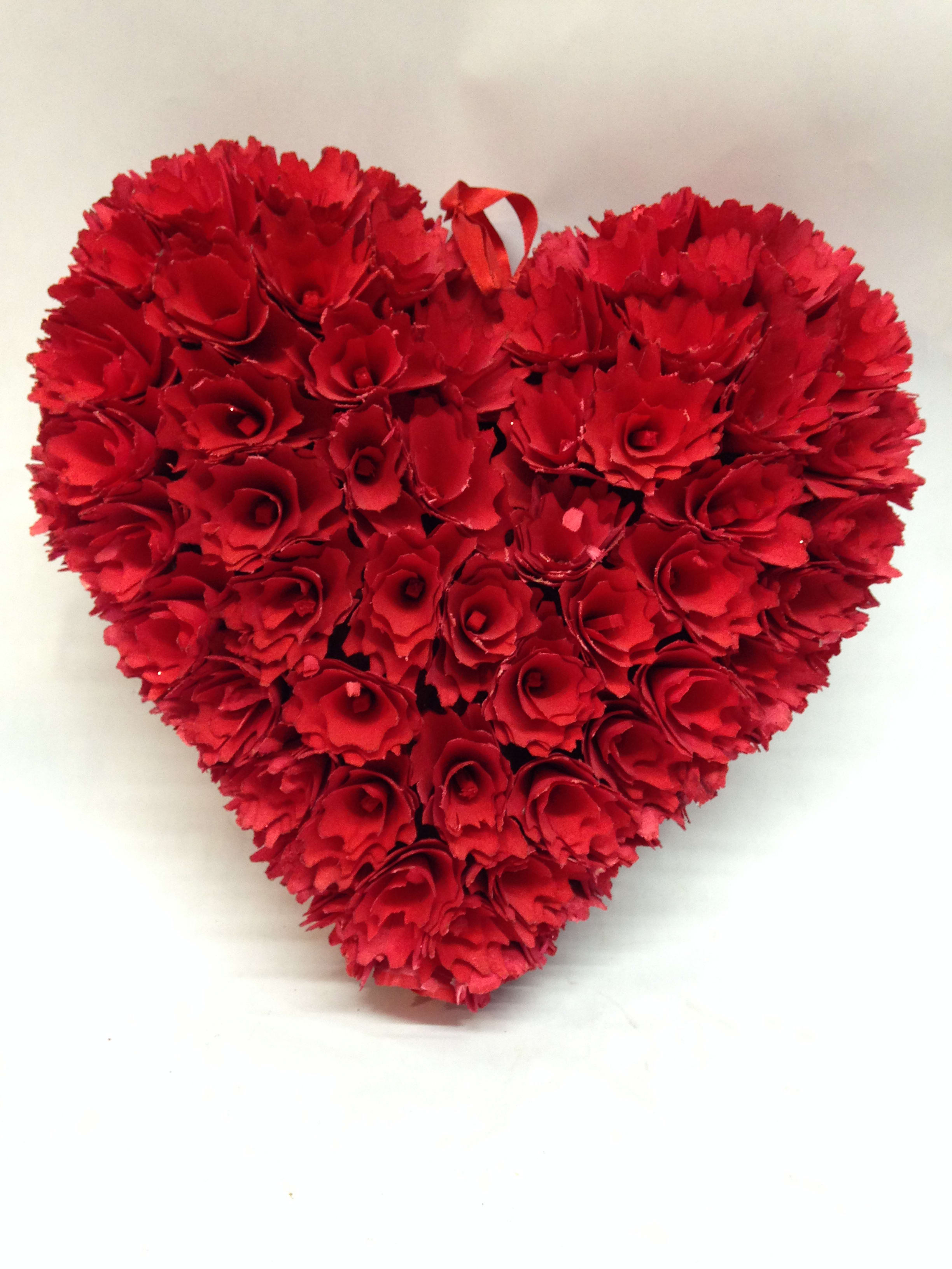 Heart-shaped arrangement of red carnations with a ribbon loop at the top
