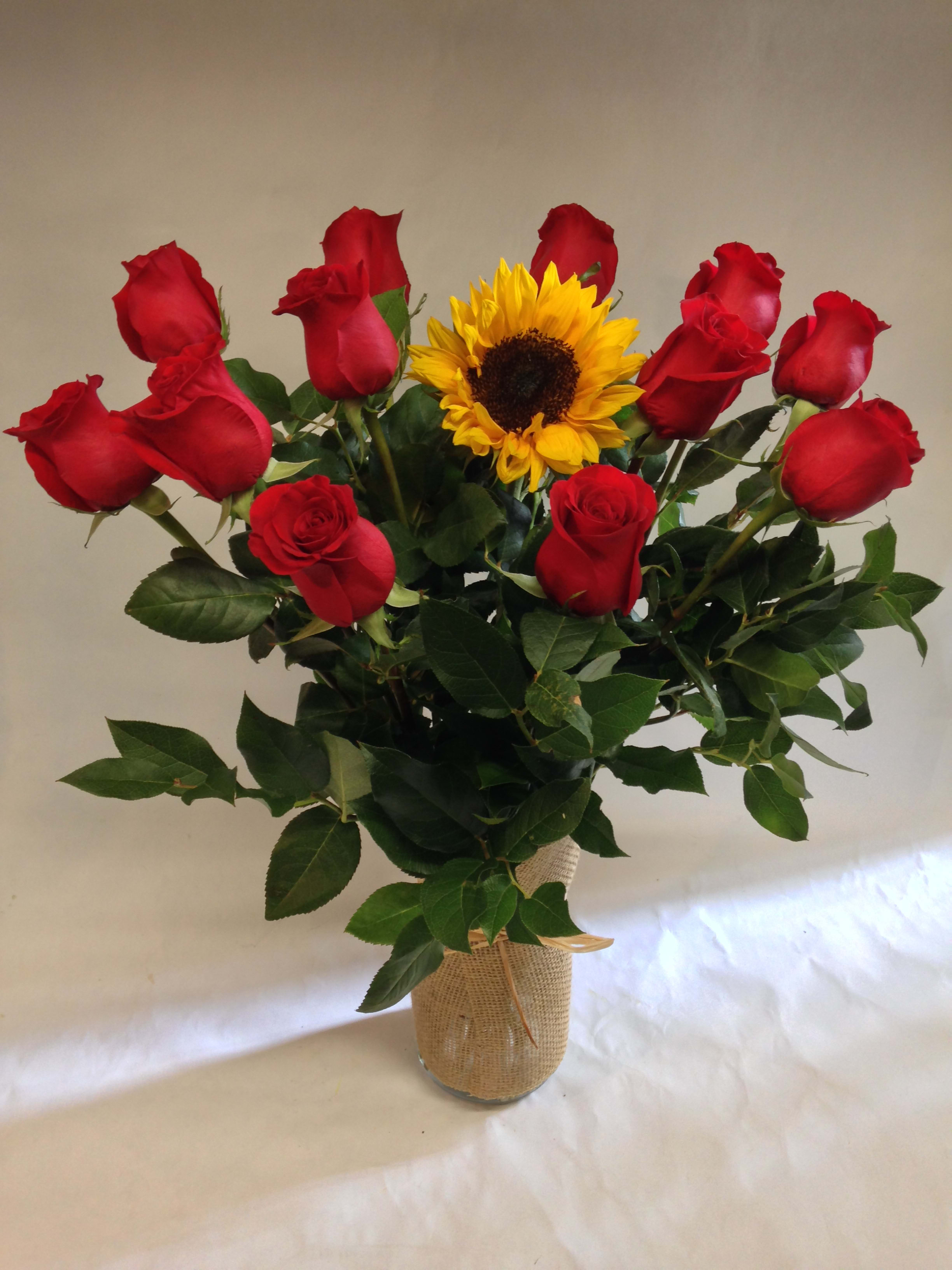 Bouquet of red roses and a sunflower in a burlap-wrapped vase