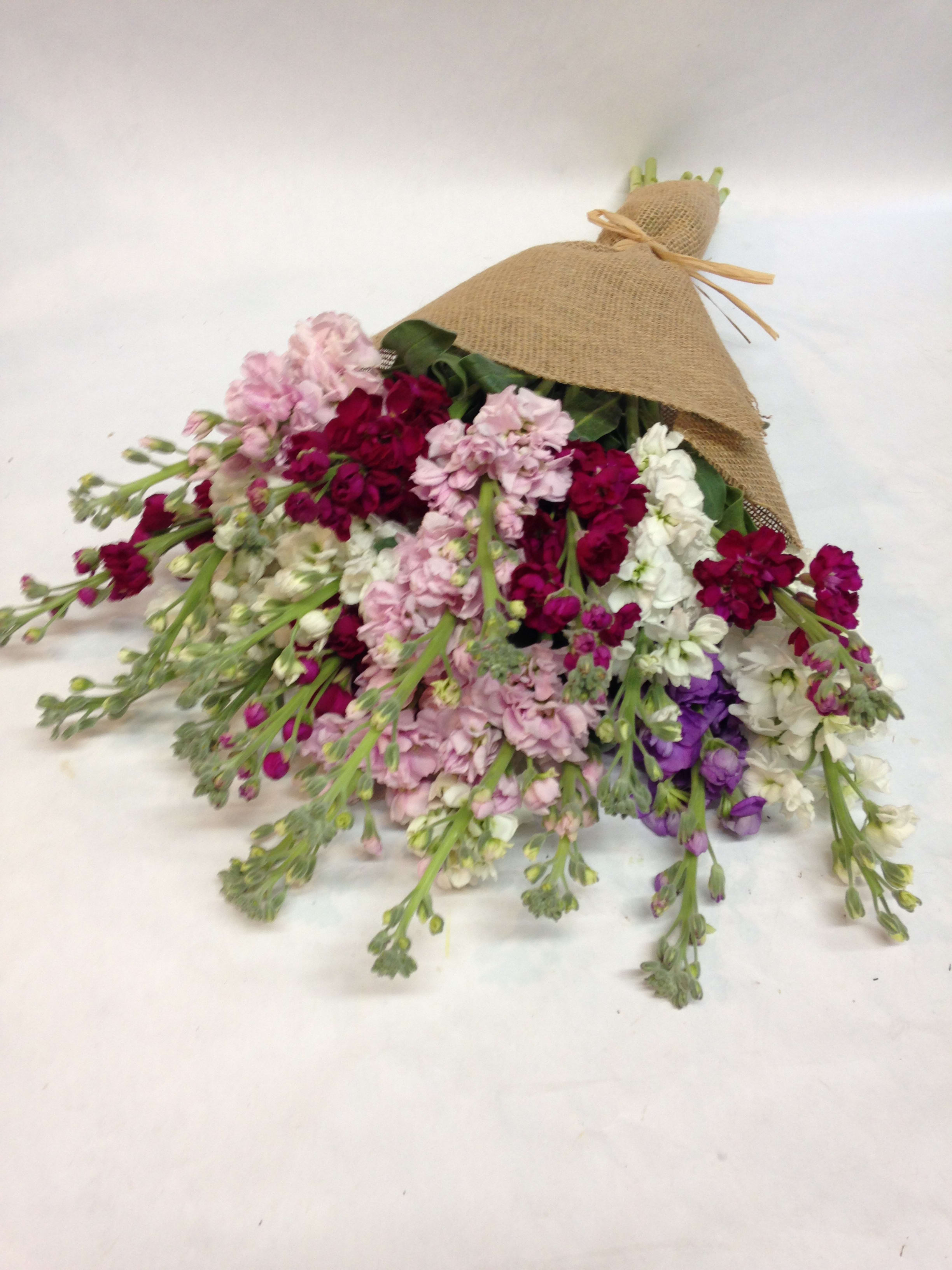 Bouquet of pink, white, and purple flowers wrapped in burlap