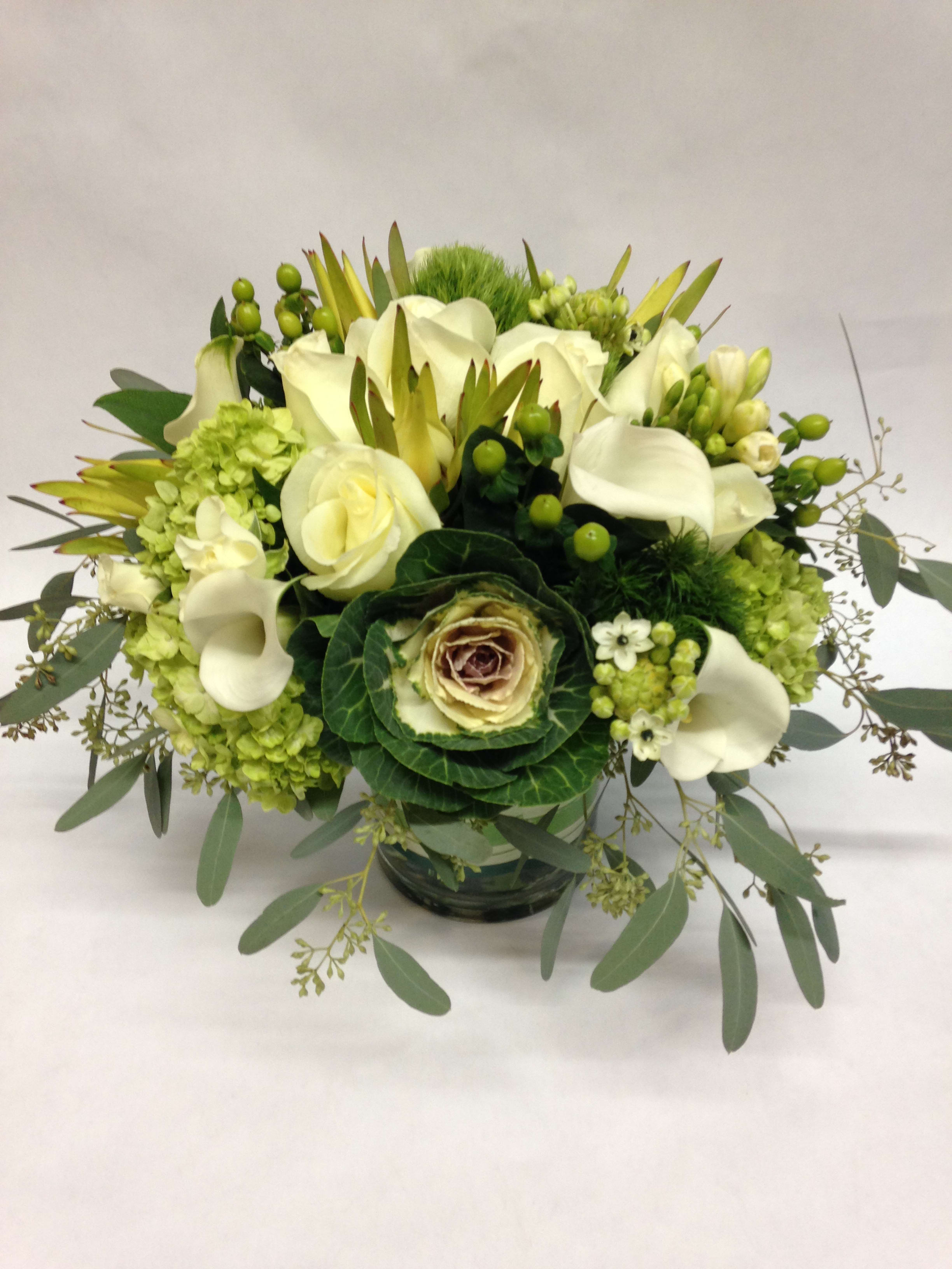 Purity - This short arrangement comes complete with kale flowers, white roses, white calla lilies, green hydrangea, dianthus, green hypericum, safari branches and seeded eucalyptus.  (Some flowers may be subject to change depending on the season. We will contact you with available flower substitutions; please contact us with specific questions if you are concerned with flower availability, thanks!)  Featured arrangement: $178.00. (Regular  Price)