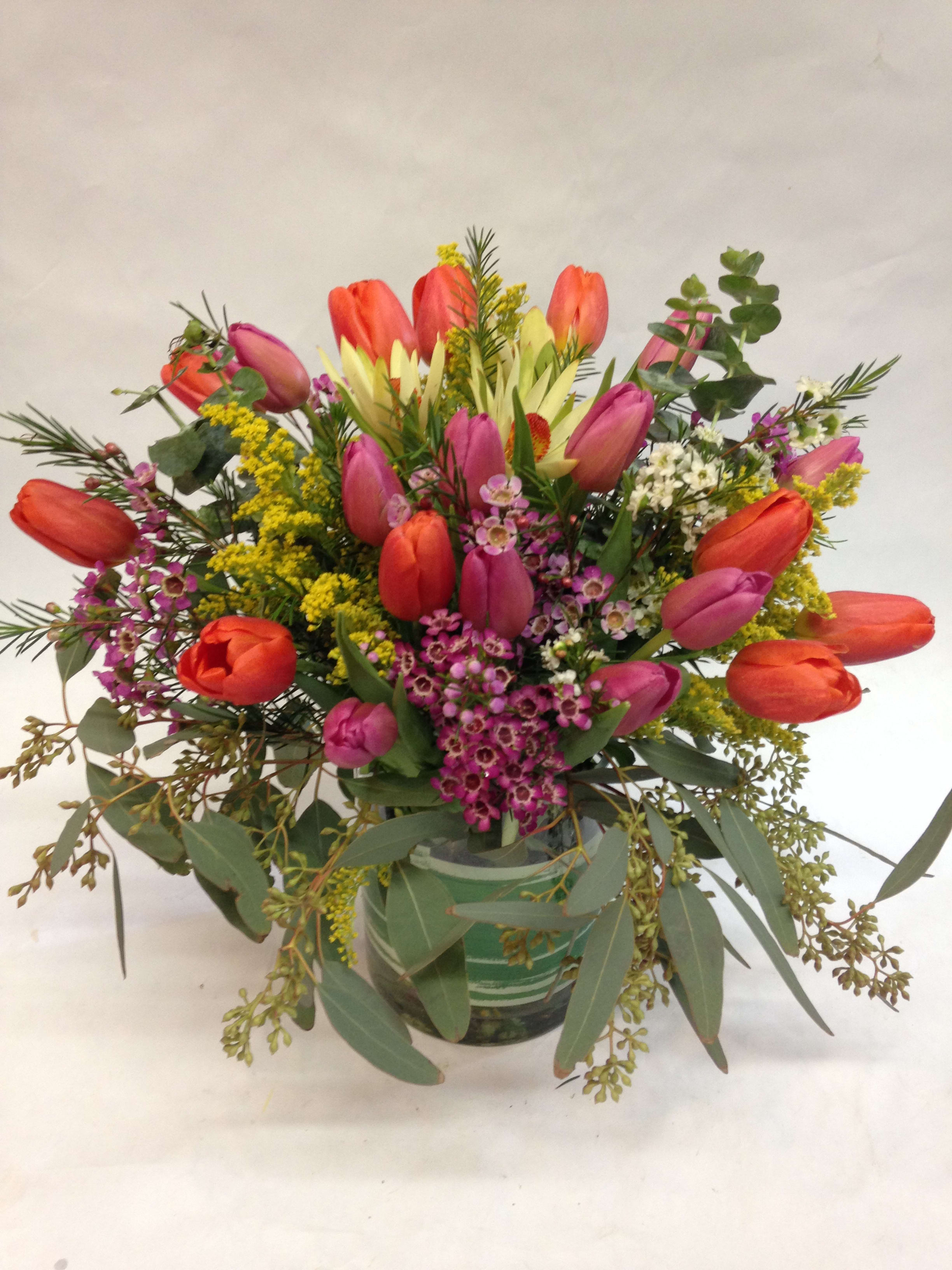 Sweet Spring - This arrangement comes complete with 20 fresh tulips, accompanied by a mixture of wax flowers, eucalyptus, solidago and greenery.  (Some flowers may be subject to change depending on the season. We will contact you with available flower substitutions; please contact us with specific questions if you are concerned with flower availability, thanks!)    Featured arrangement: $128.75 (Regular Price)
