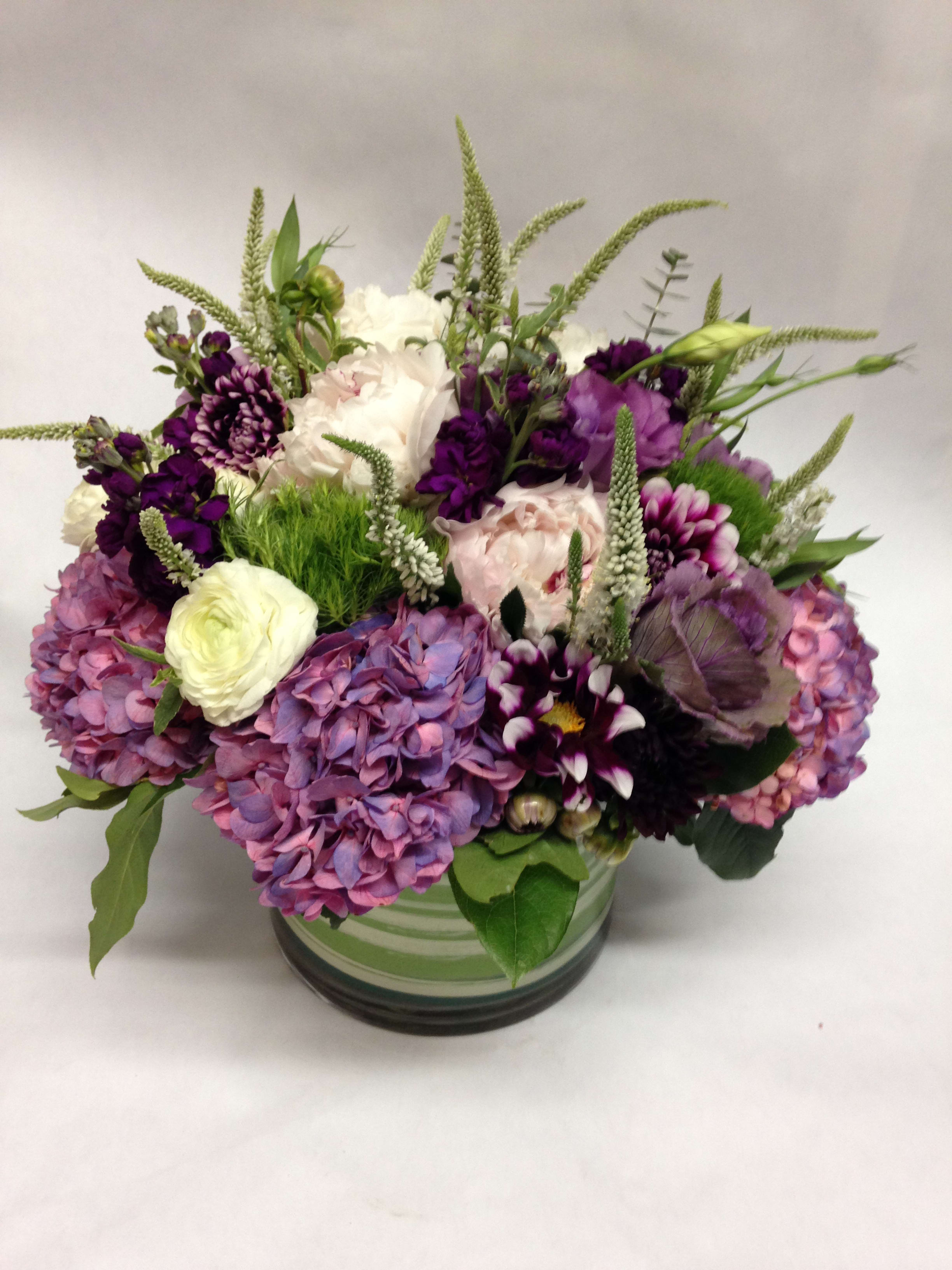 Mixed purple and white flowers arranged in a glass vase
