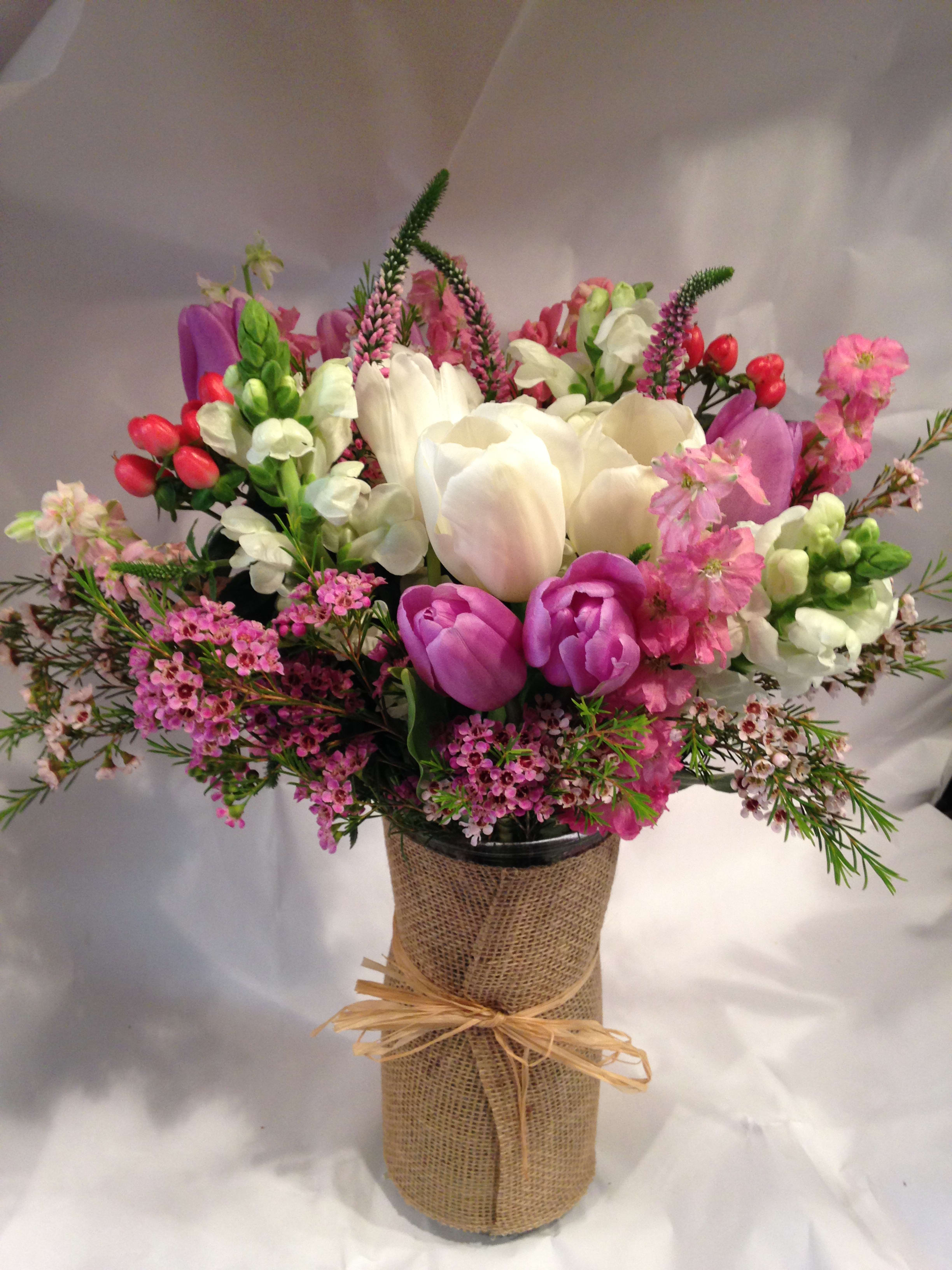 Bouquet of pink, white, and purple flowers in a burlap-wrapped vase