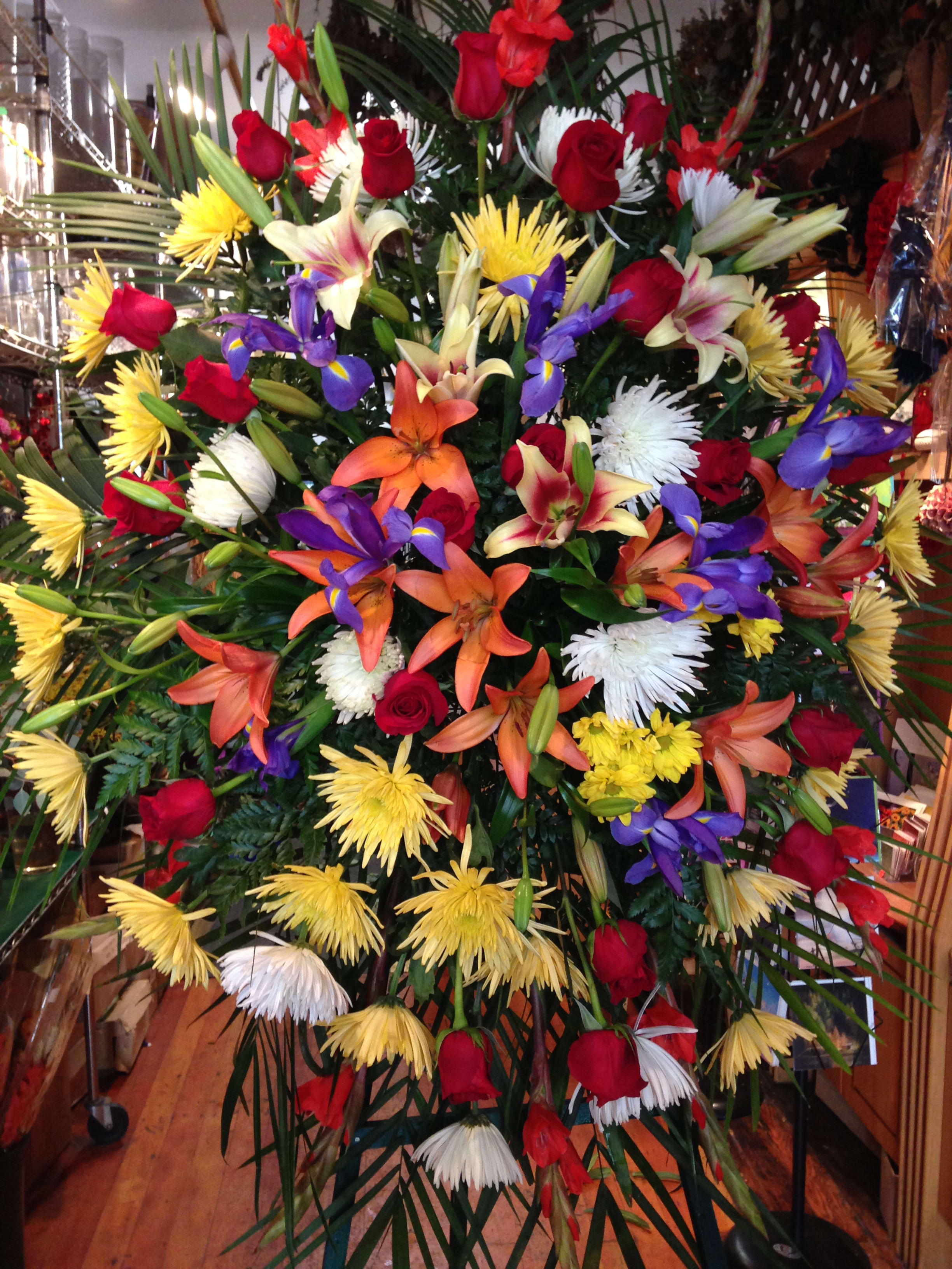 Large mixed floral spray with red roses, lilies, and yellow and white blooms