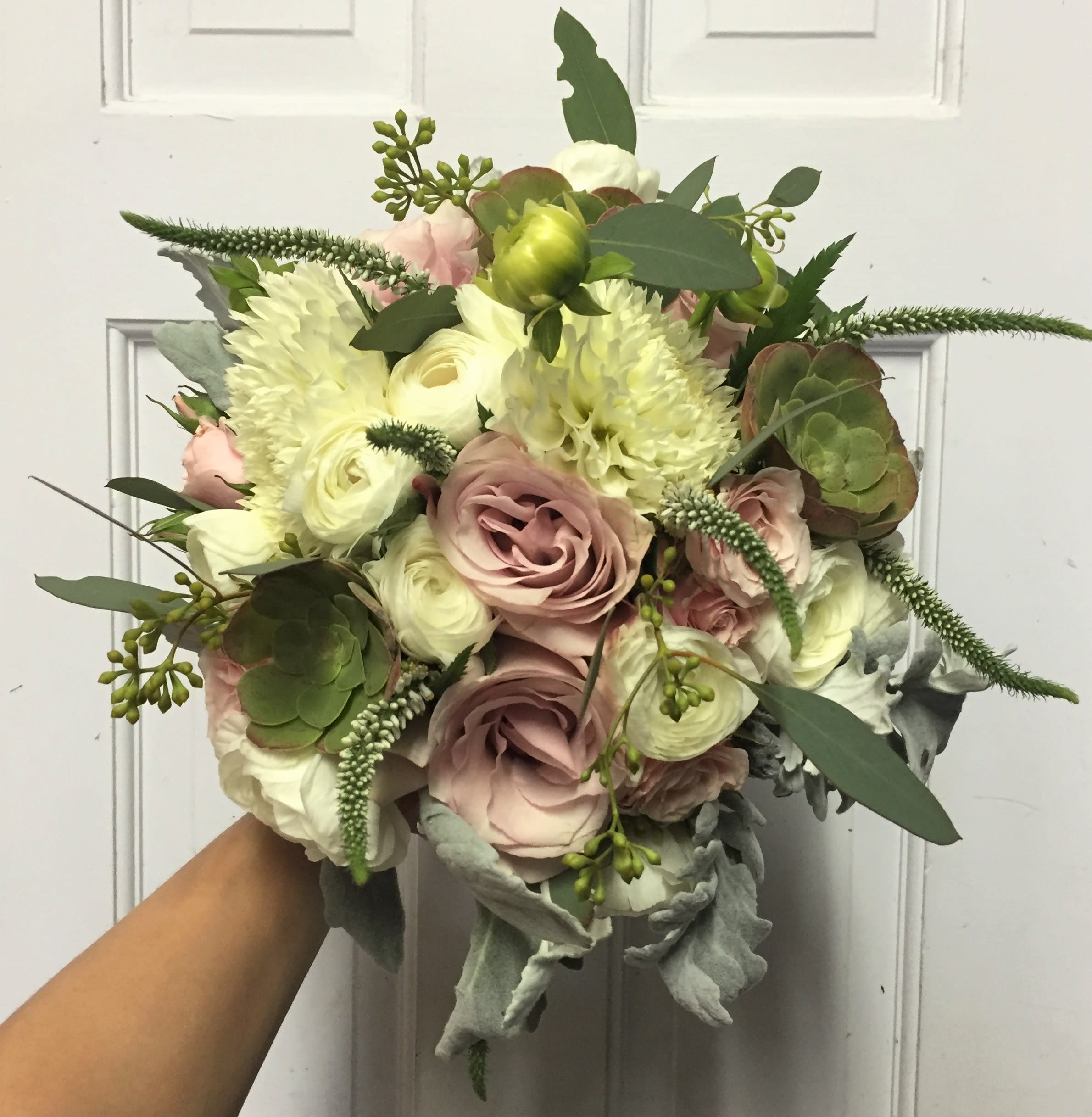 Handheld bouquet of blush and white flowers with greenery