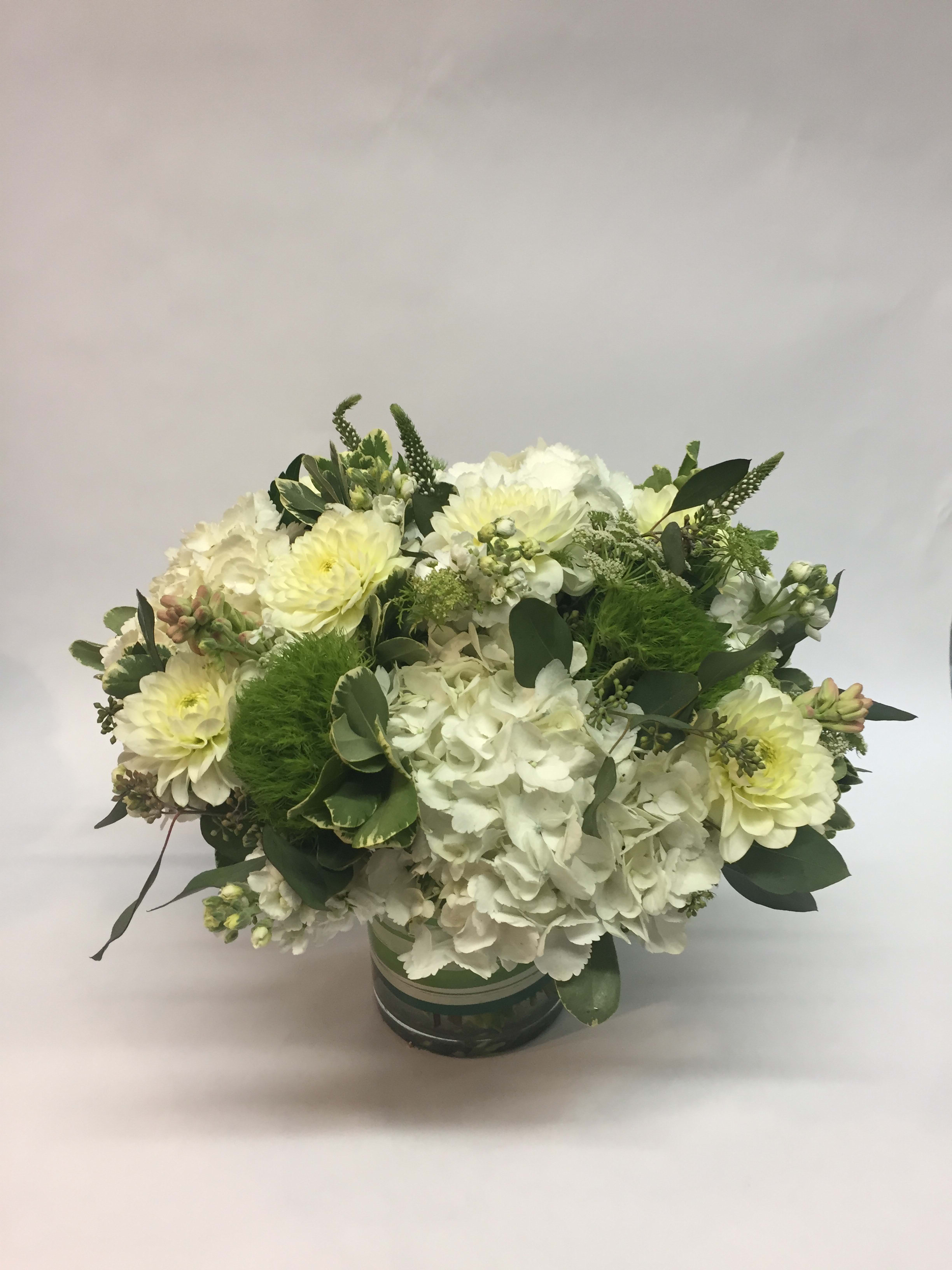 White and pale yellow floral arrangement in a round container