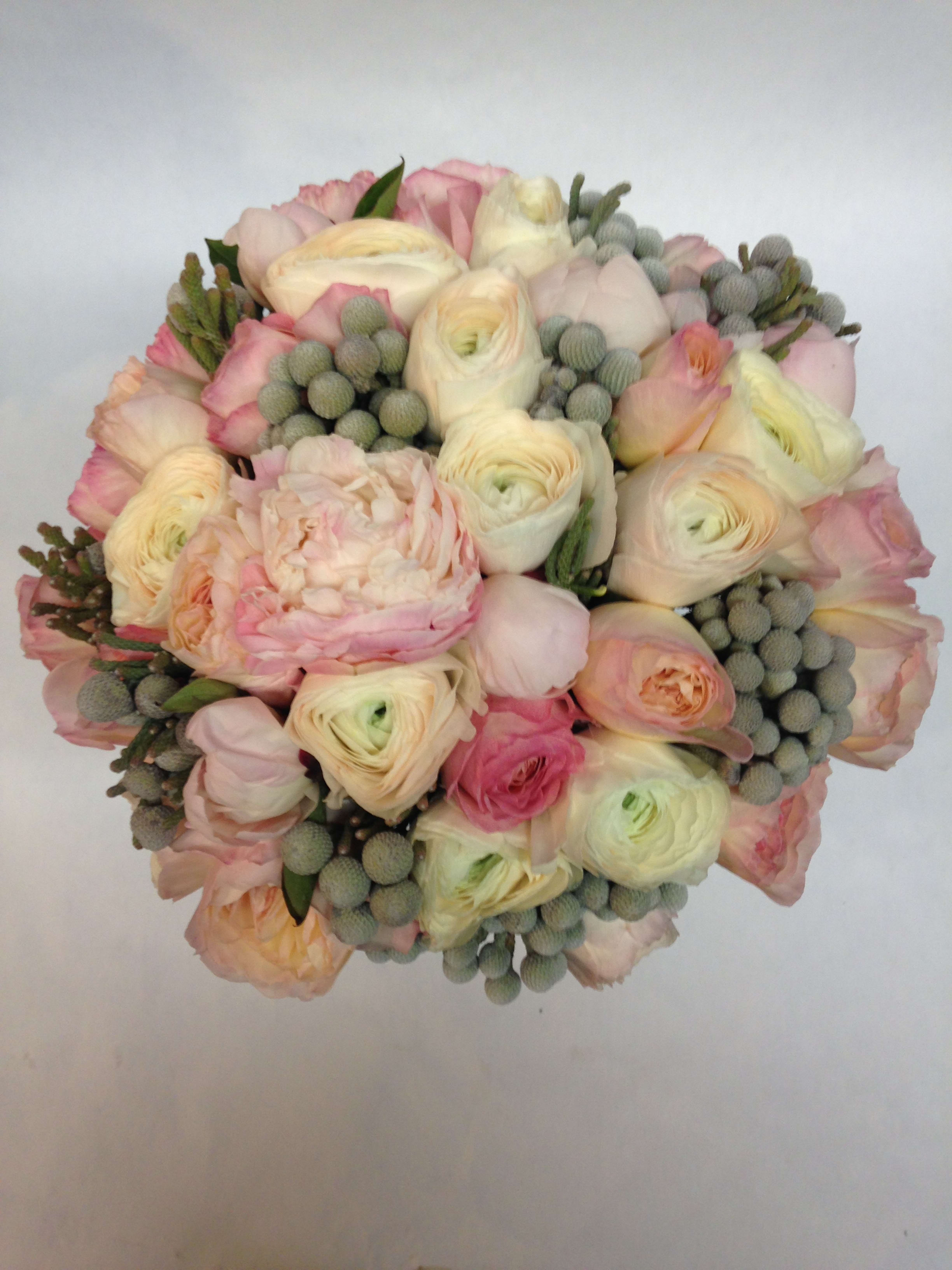 Round bouquet of pale pink and cream flowers with gray berry accents