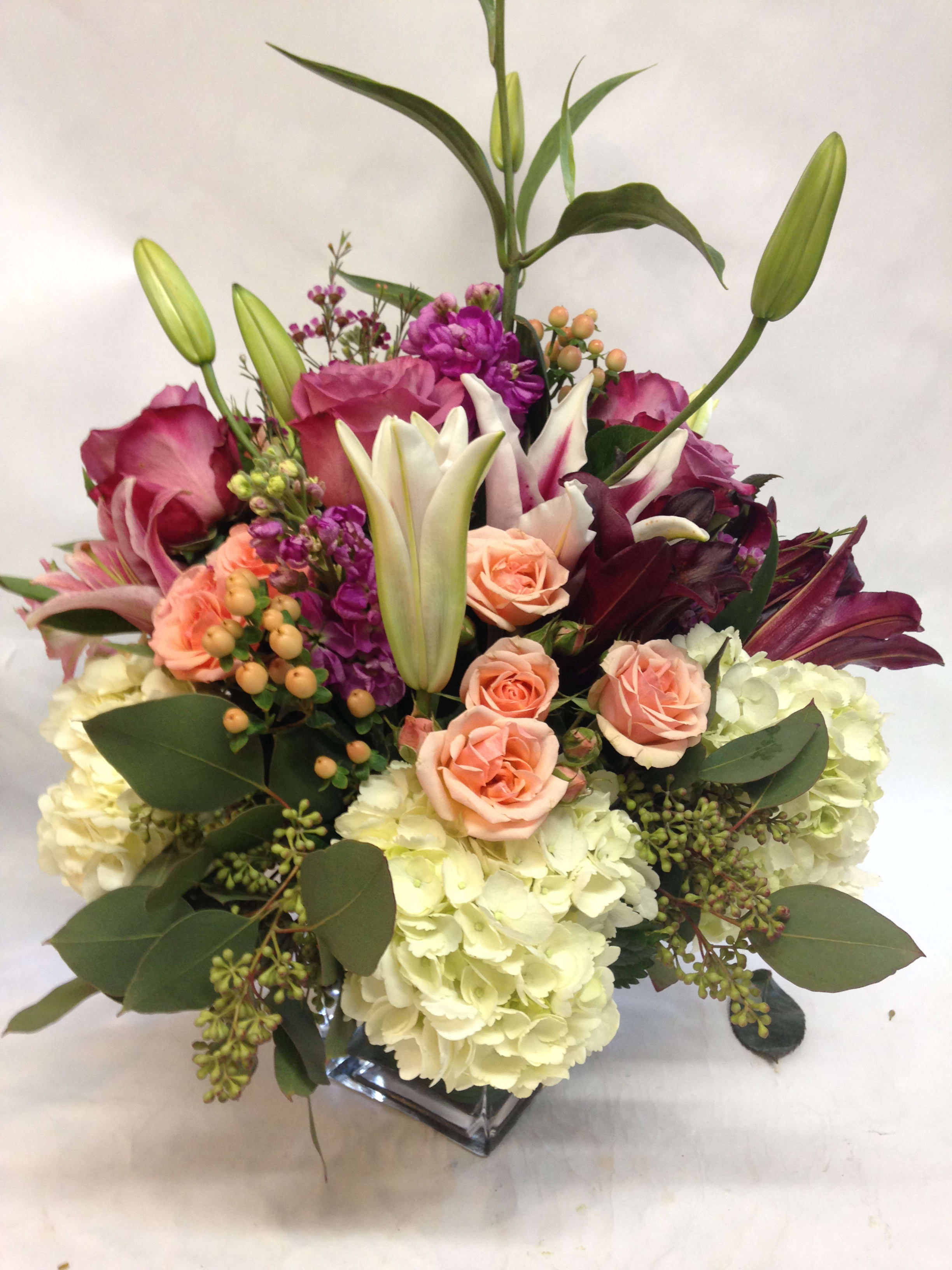 Bouquet of pink roses, lilies, and hydrangeas in a glass vase