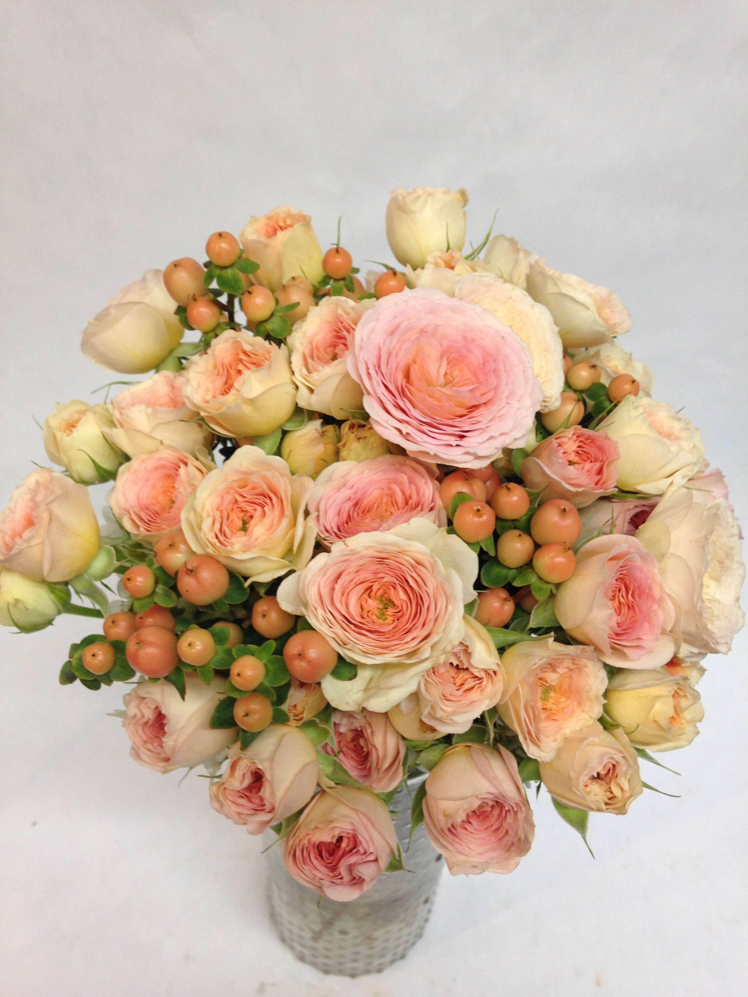 Bouquet of blush roses and peach ranunculus in a woven vase