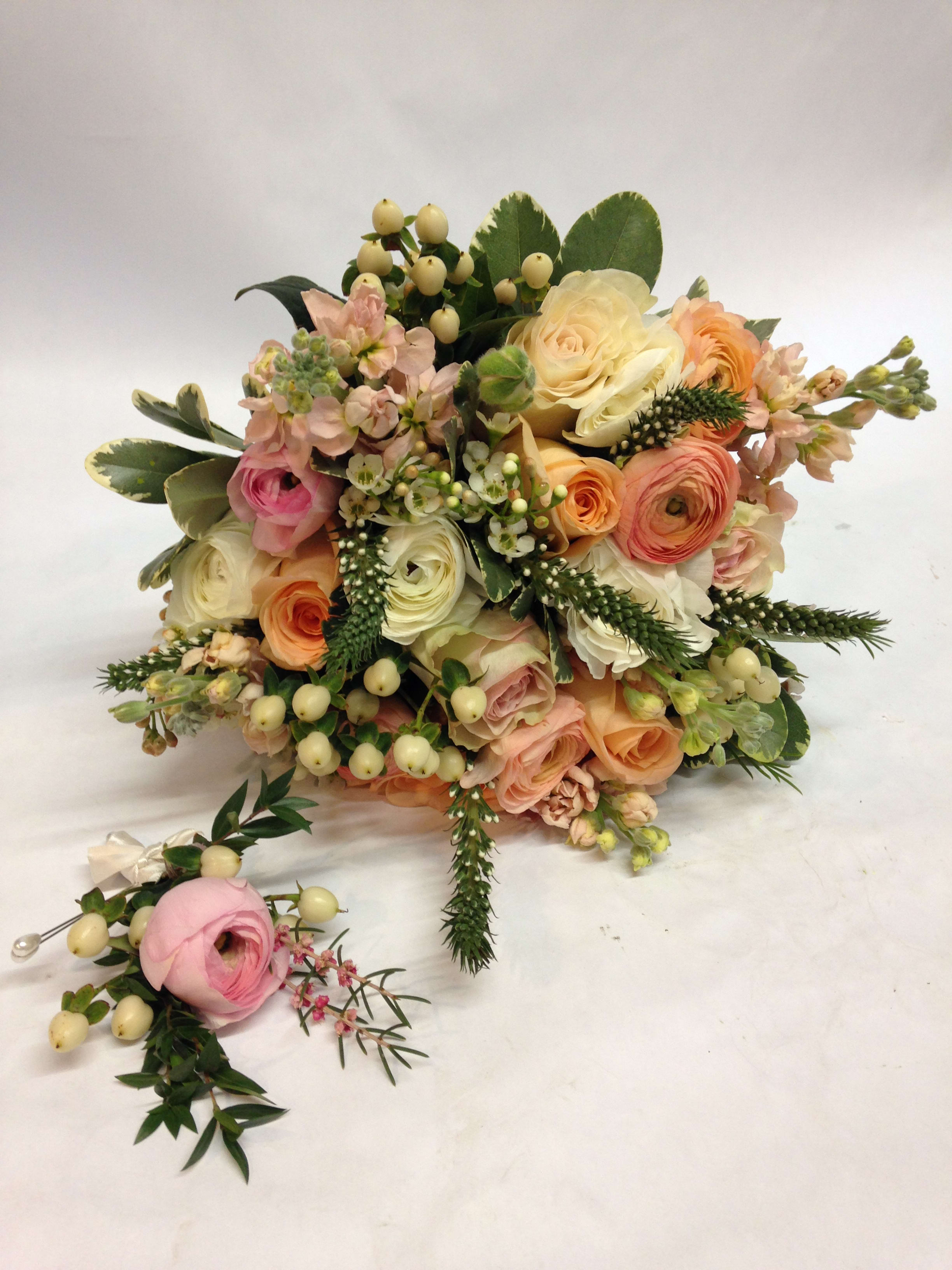 Pastel bouquet of roses and ranunculus with berries and greenery