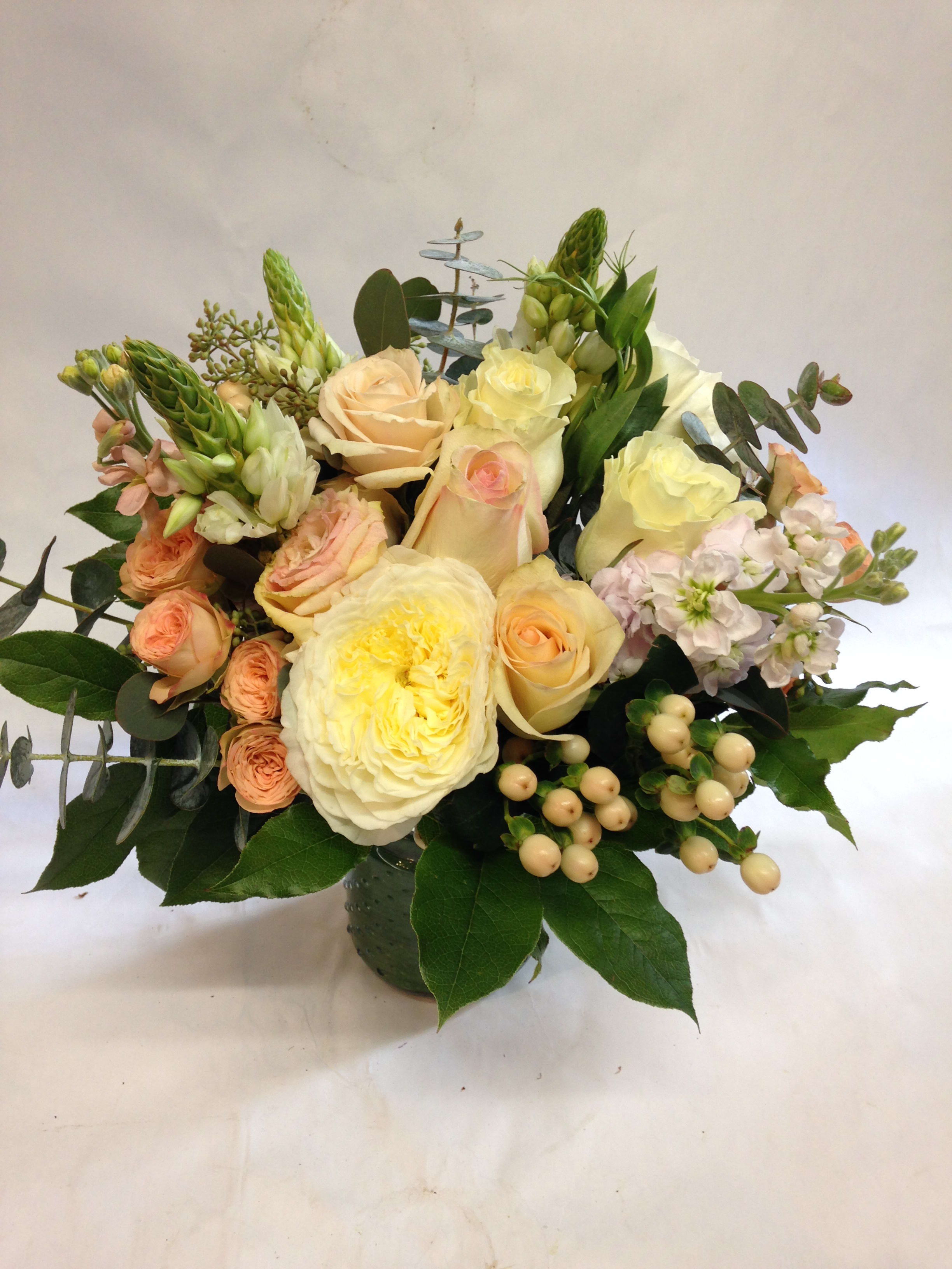 Bouquet of cream and peach roses with pale pink flowers in a vase