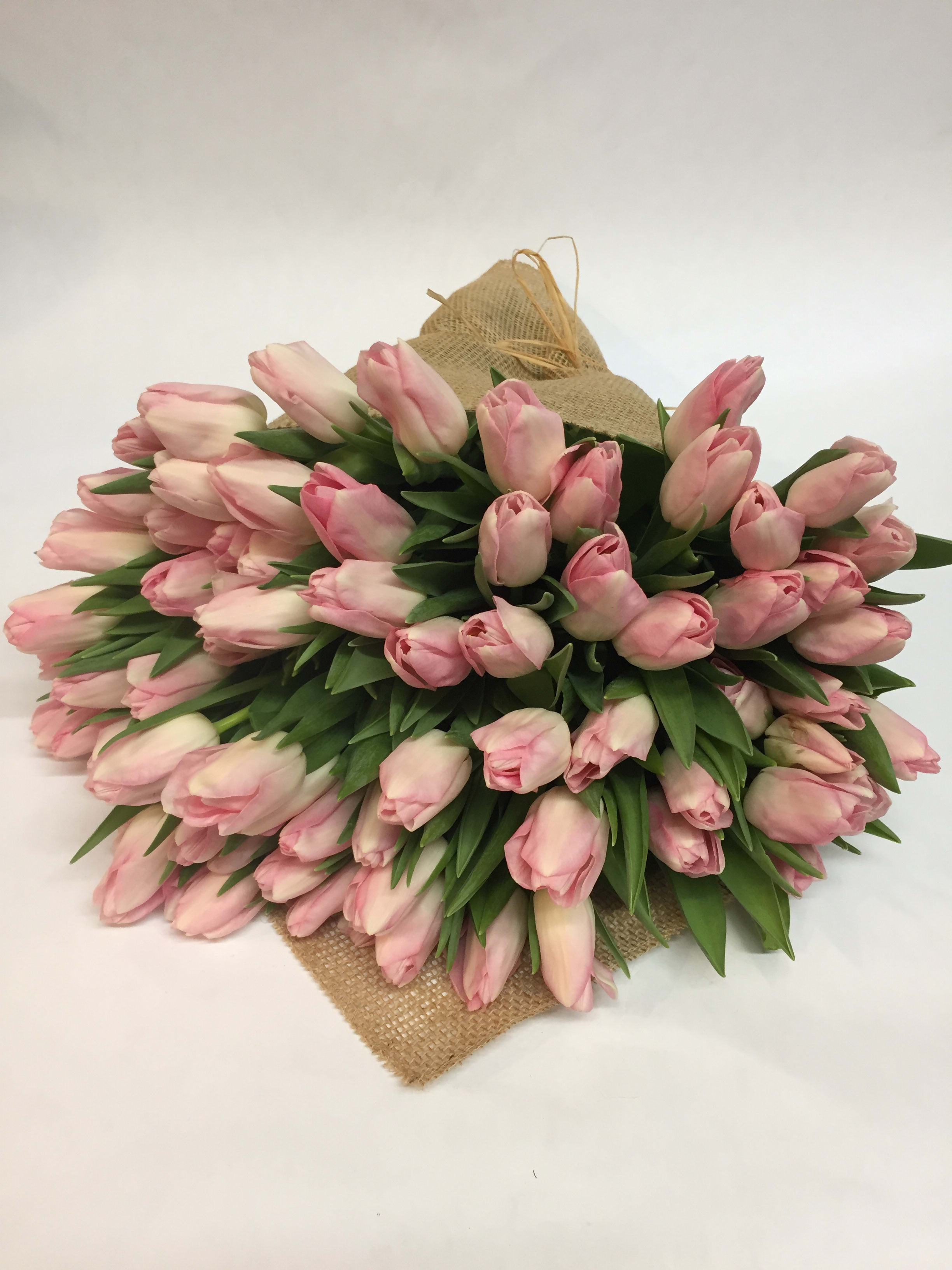 Large bouquet of pale pink tulips wrapped in burlap