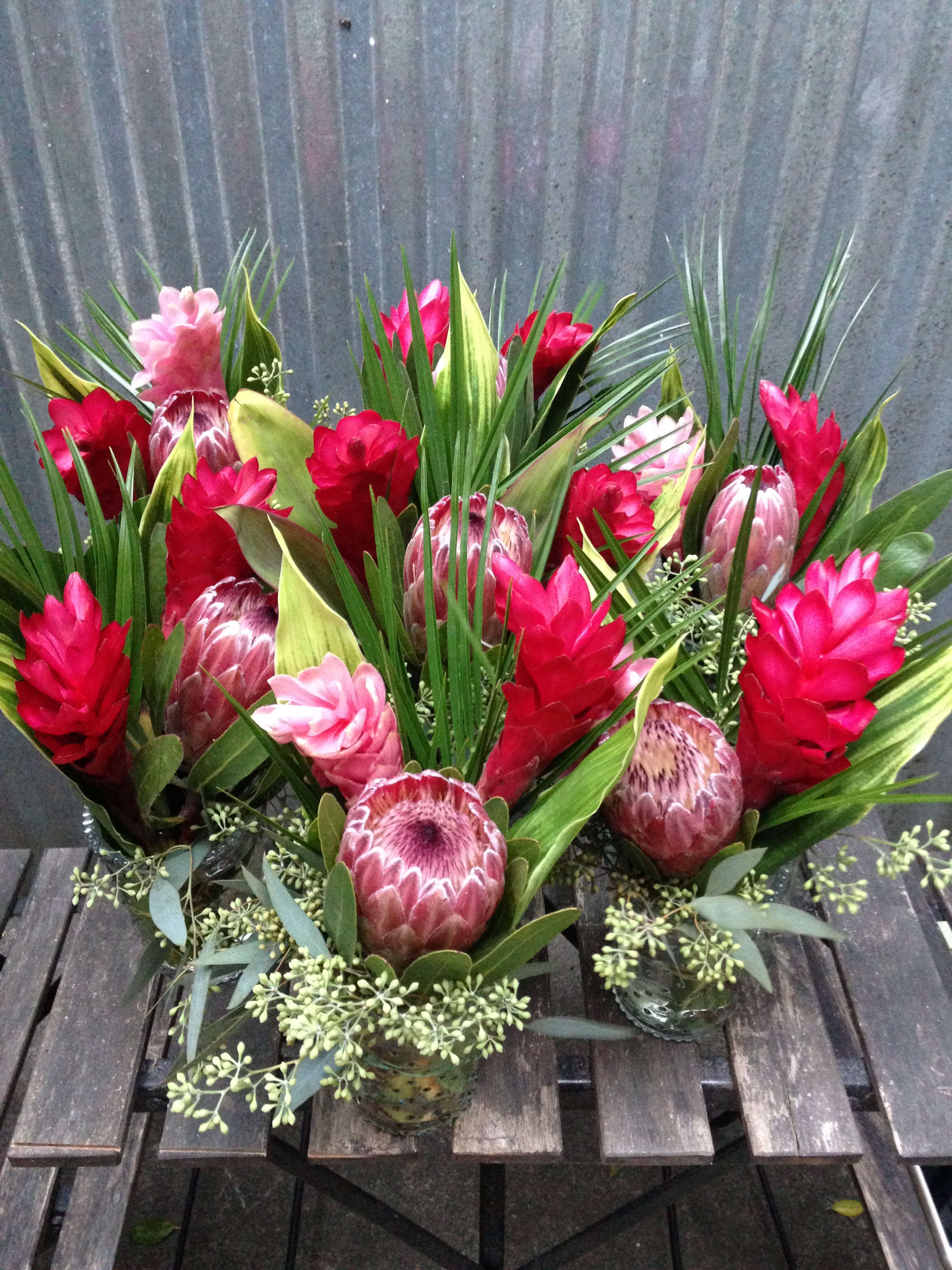Tropical floral arrangements with red and pink blooms in small glass vases