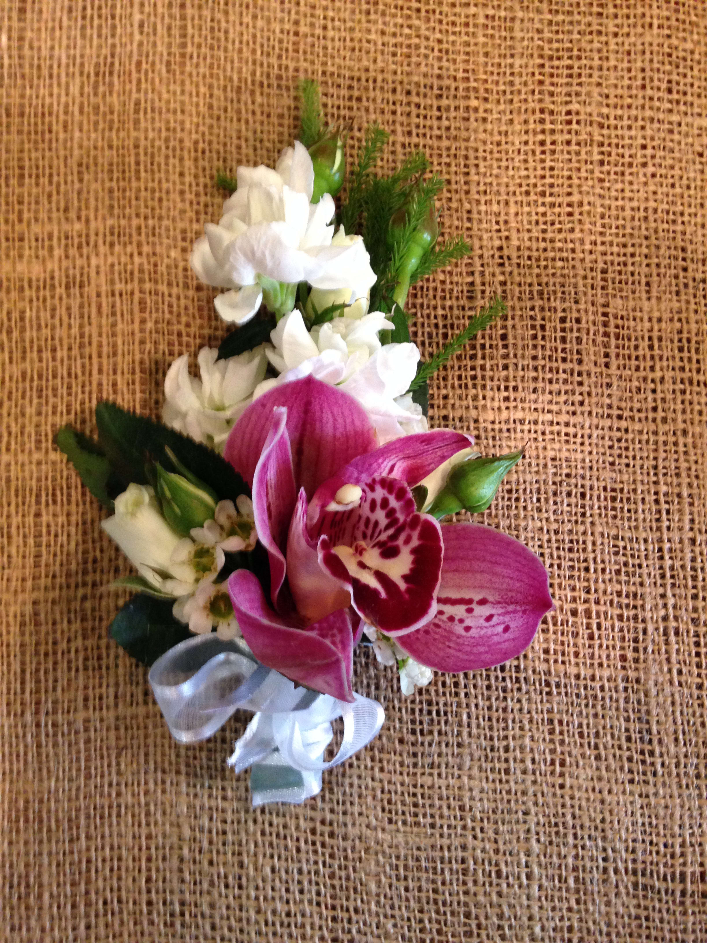 Pink orchid corsage with white flowers and a silver ribbon