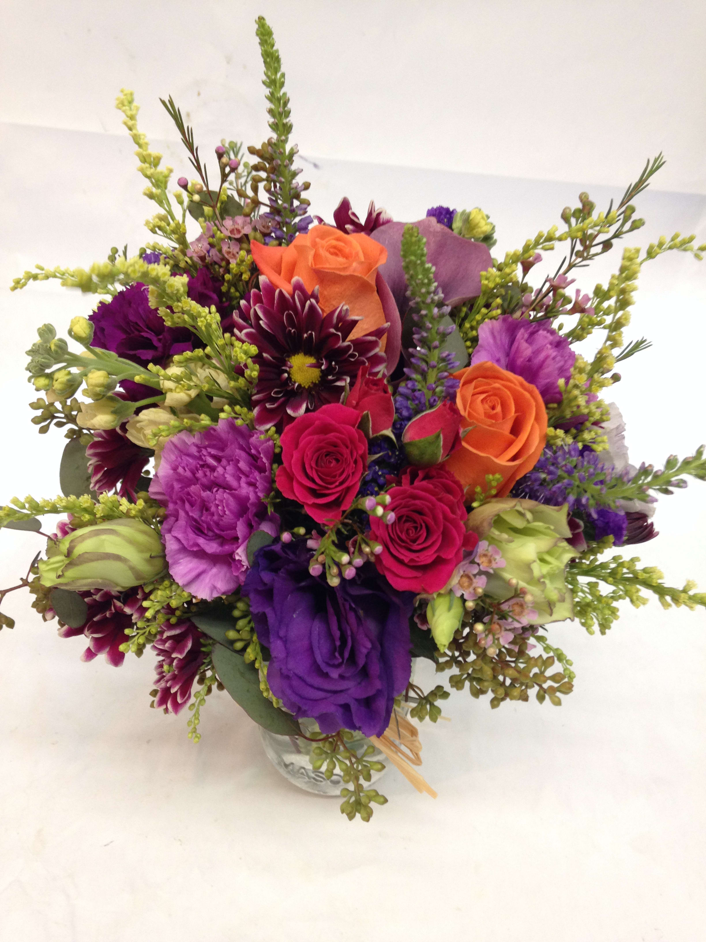 Mixed bouquet of purple, pink, and orange flowers in a glass vase