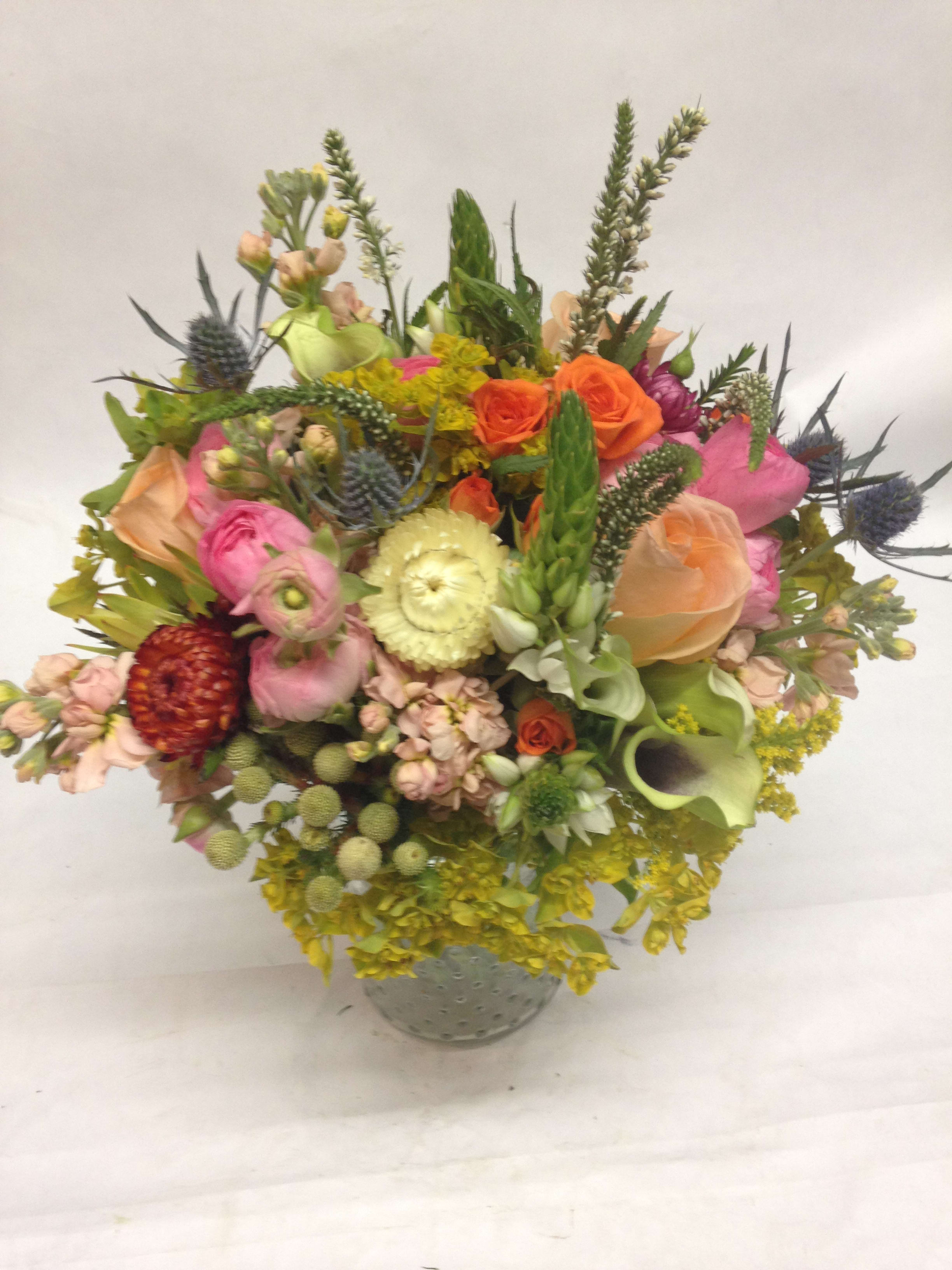 Mixed bouquet in a gray vase with pink, orange, yellow, and green blooms