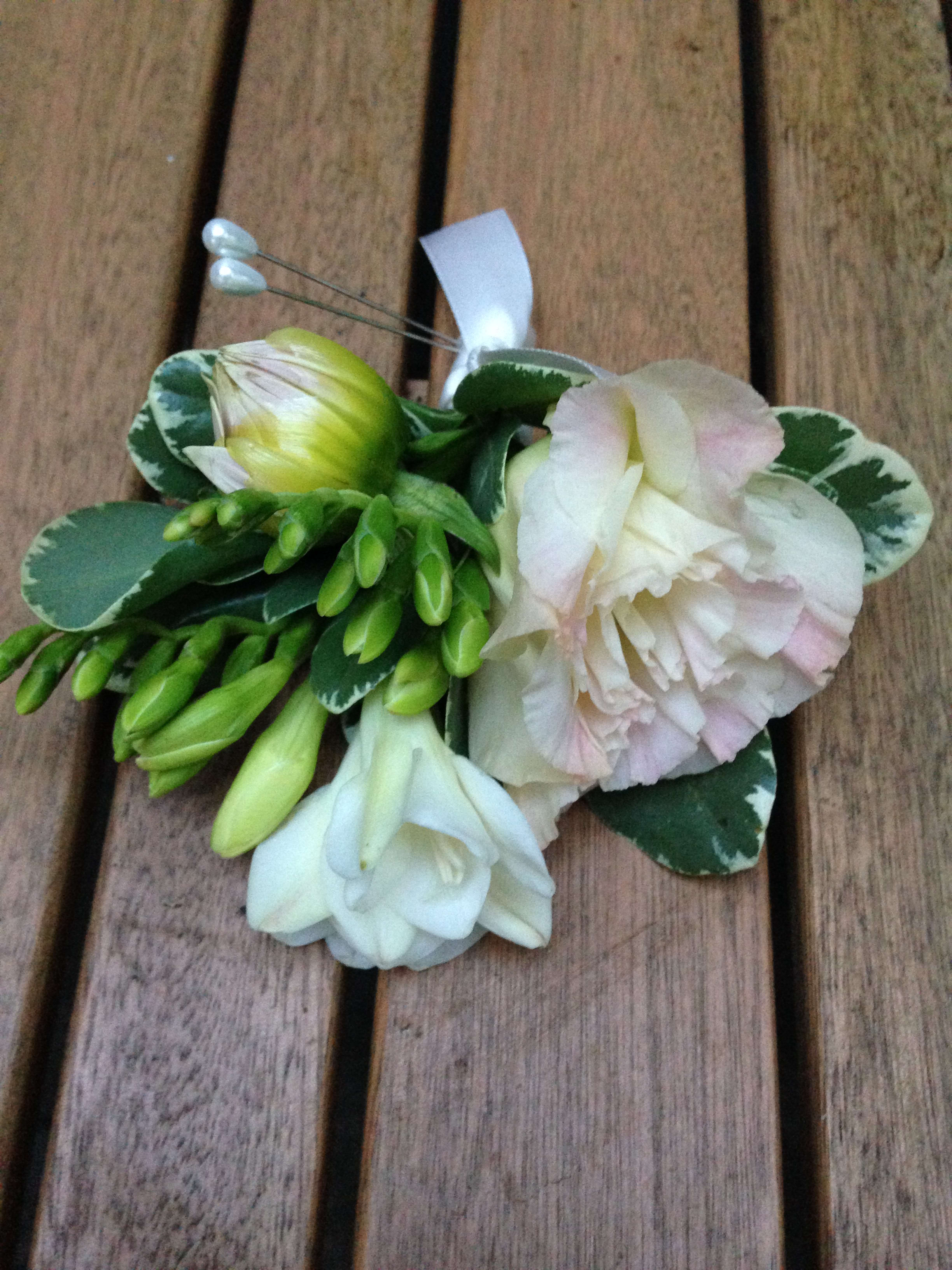 Small floral corsage with white and pale pink blooms on a ribbon tie