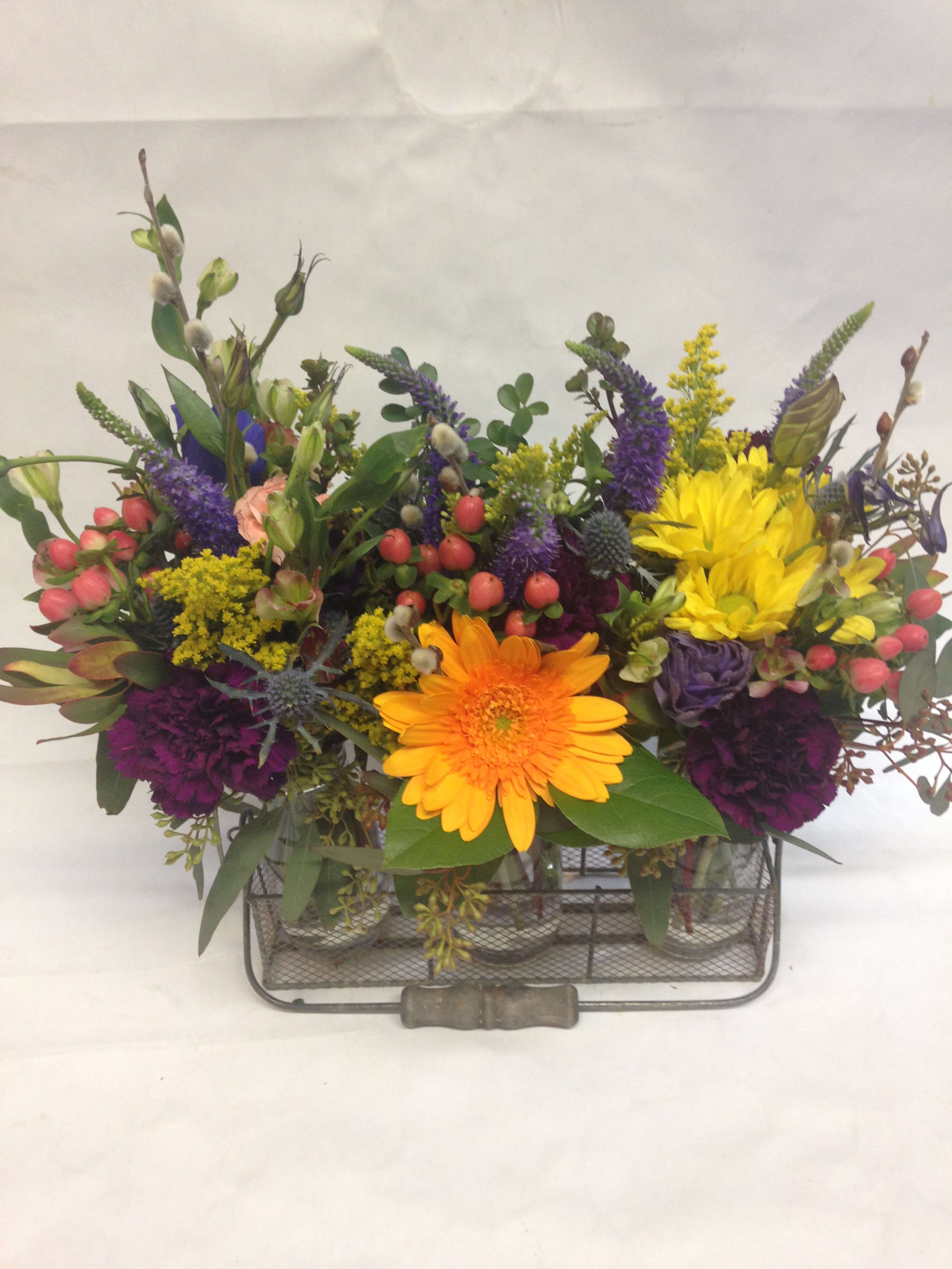 Colorful mixed flower arrangement in a metal basket