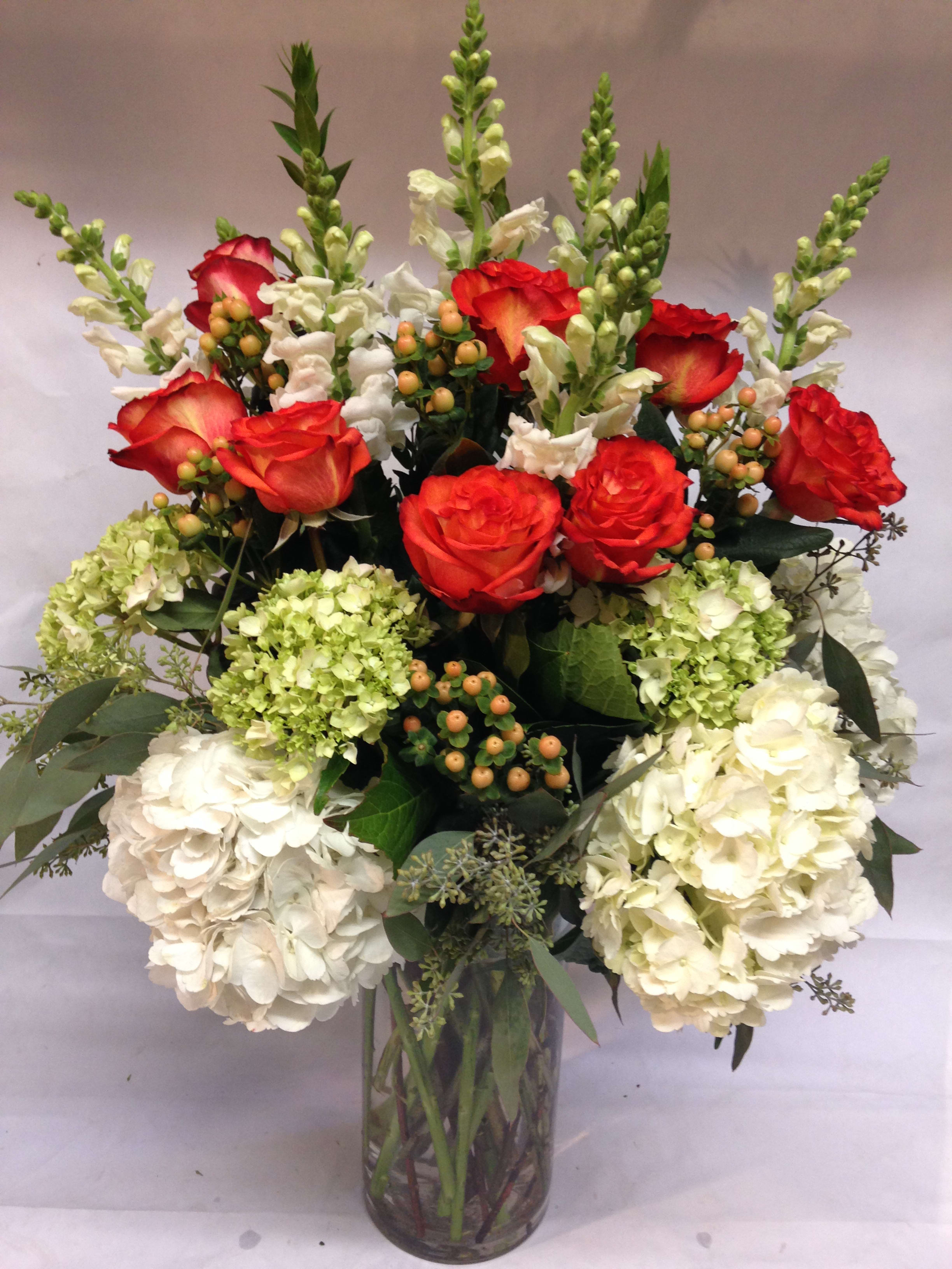 Red roses and white hydrangeas in a clear glass vase