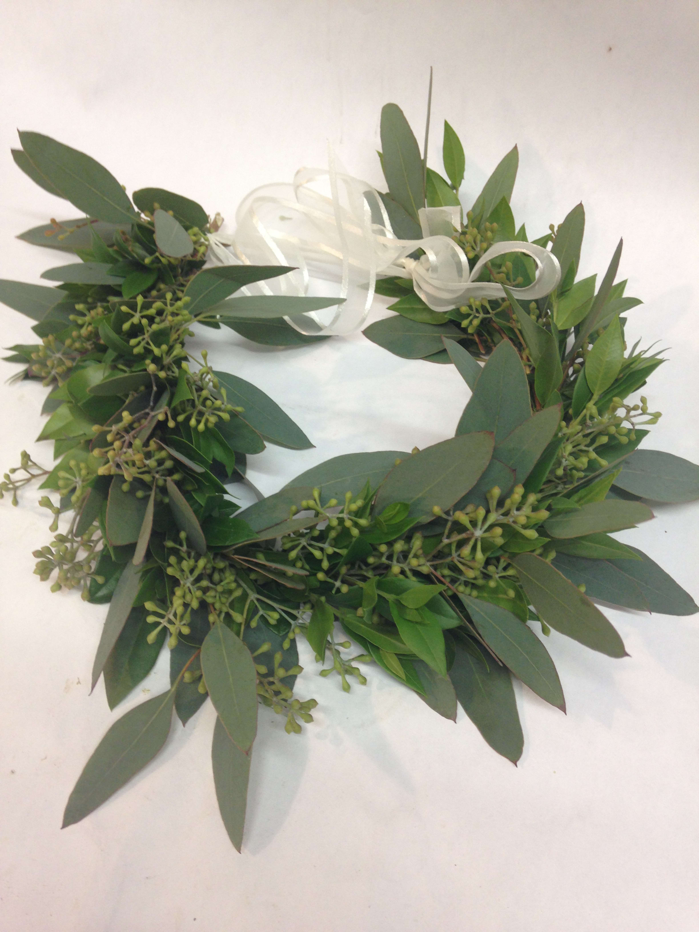 Green foliage wreath with a white ribbon bow