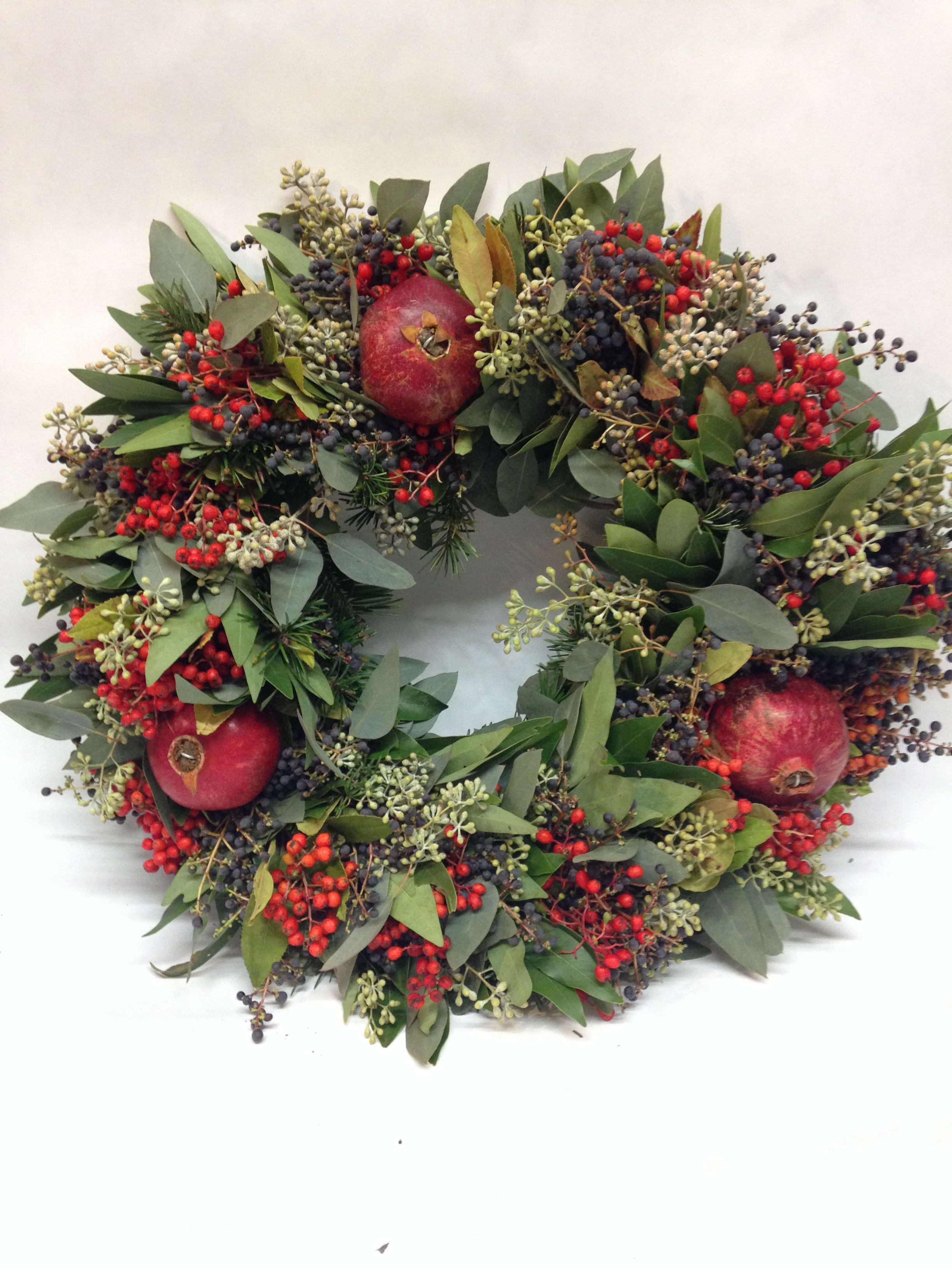 Pomegranate Christmas Wreath - A beautiful wreath filled with seasonal greenery including, fragrant eucalyptus and bay leaf. Accents of berries and fresh pomegranates make this wrath a sophisticated addition to your home. Measures approximately 18-19 inches in diameter. Featured Wreath: $155.00