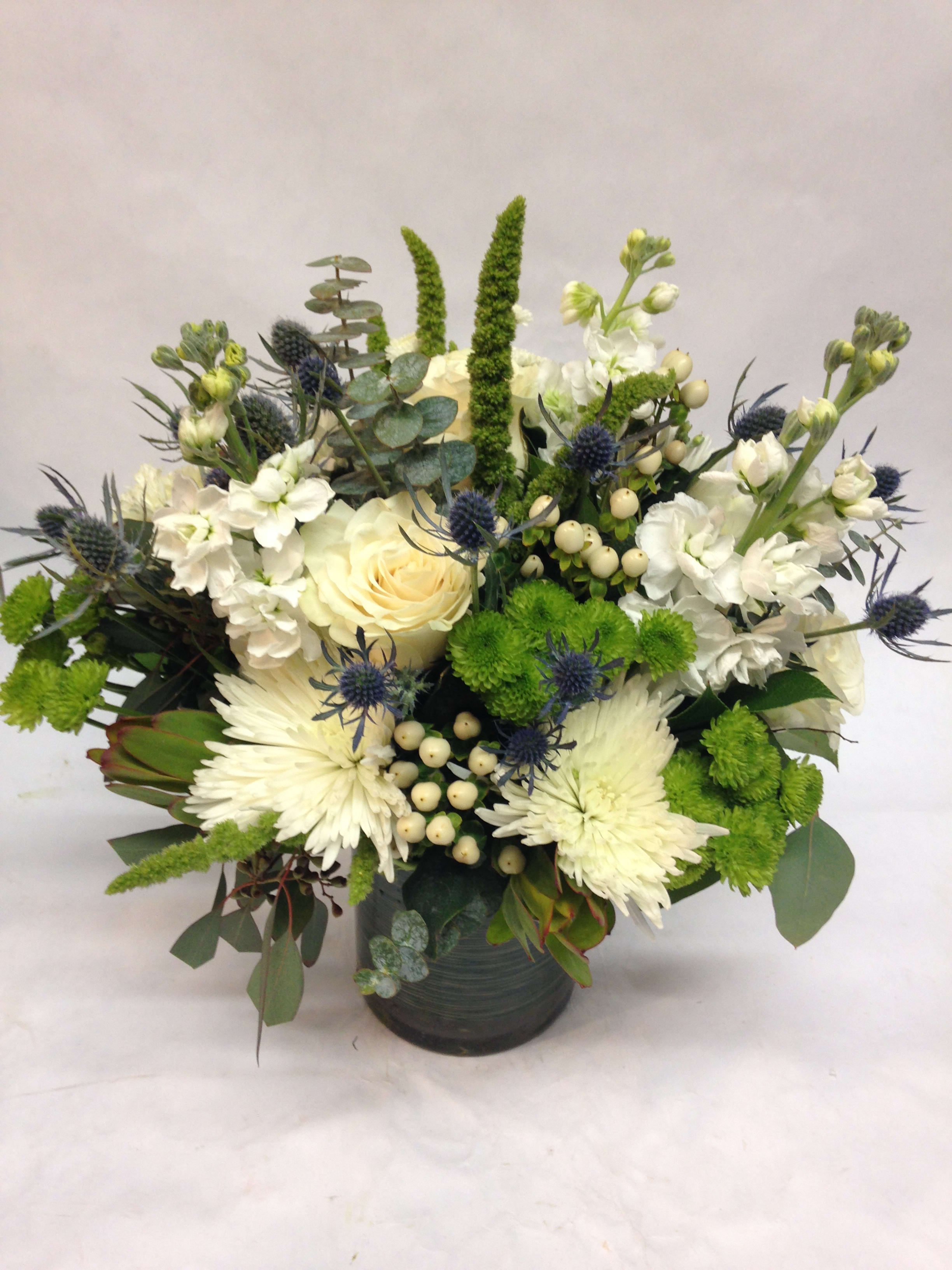White and green floral arrangement in a dark vase
