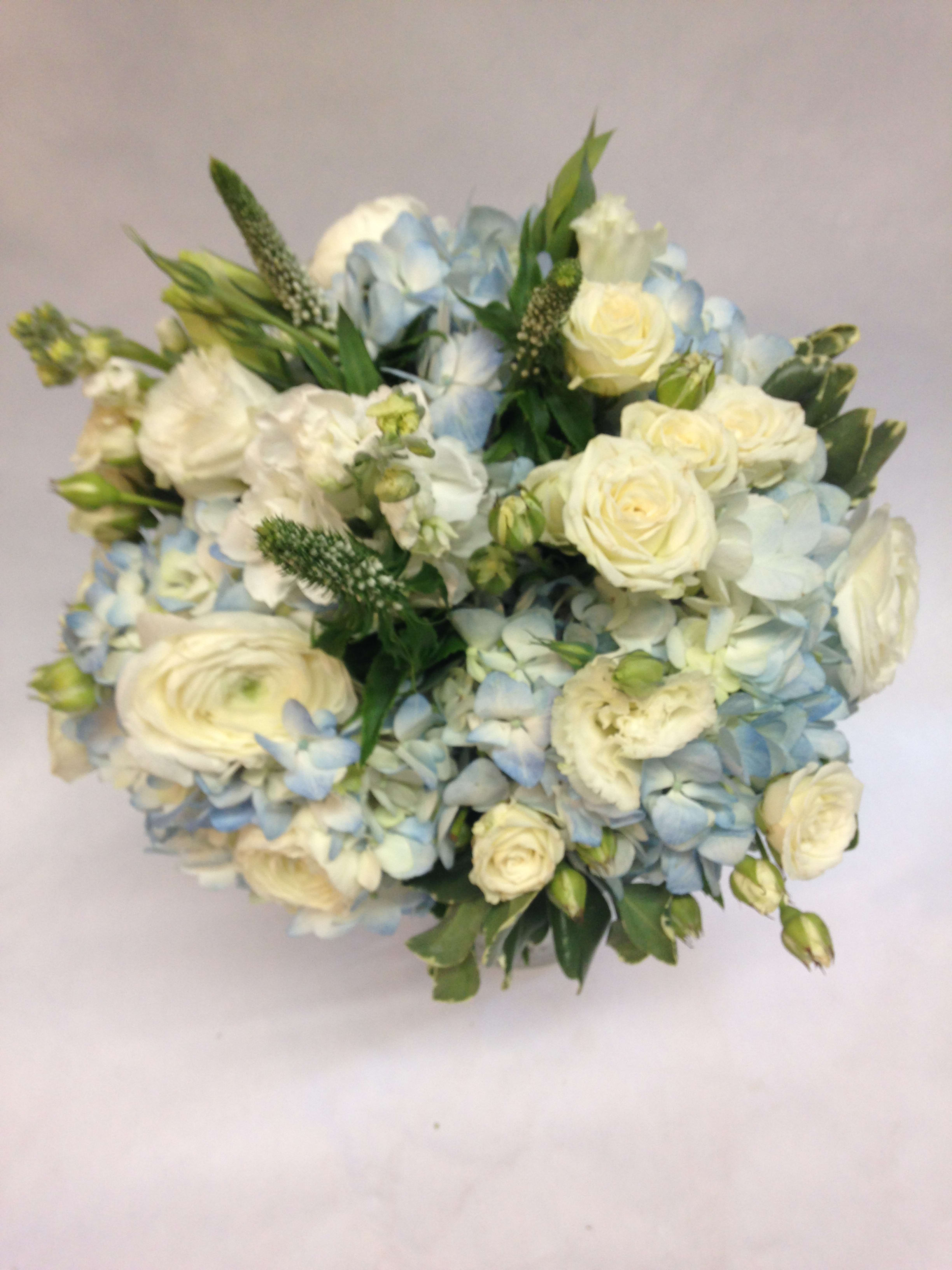 Bouquet of white roses and pale blue hydrangeas with green accents