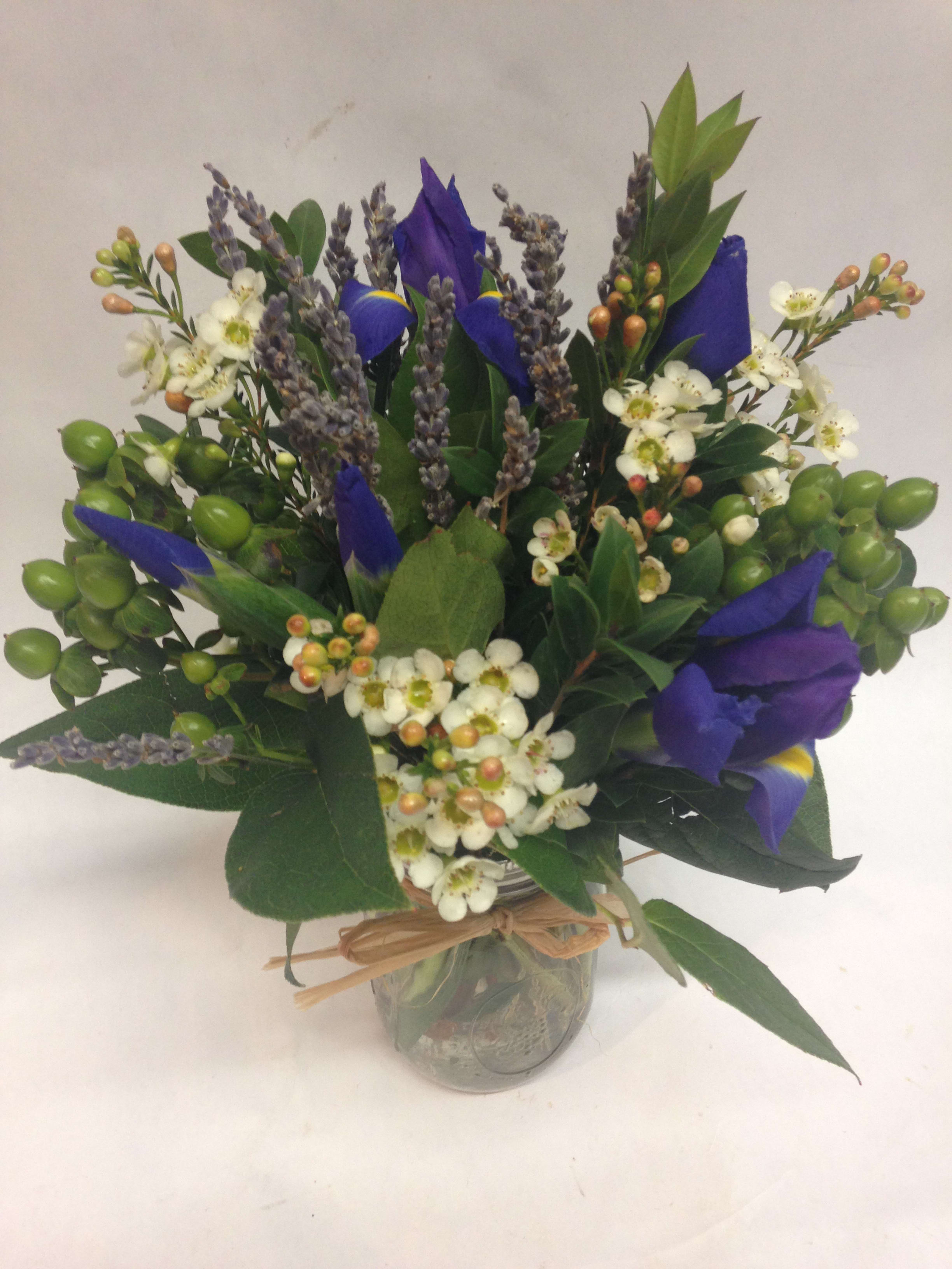 Blue iris bouquet with white blossoms in a glass jar