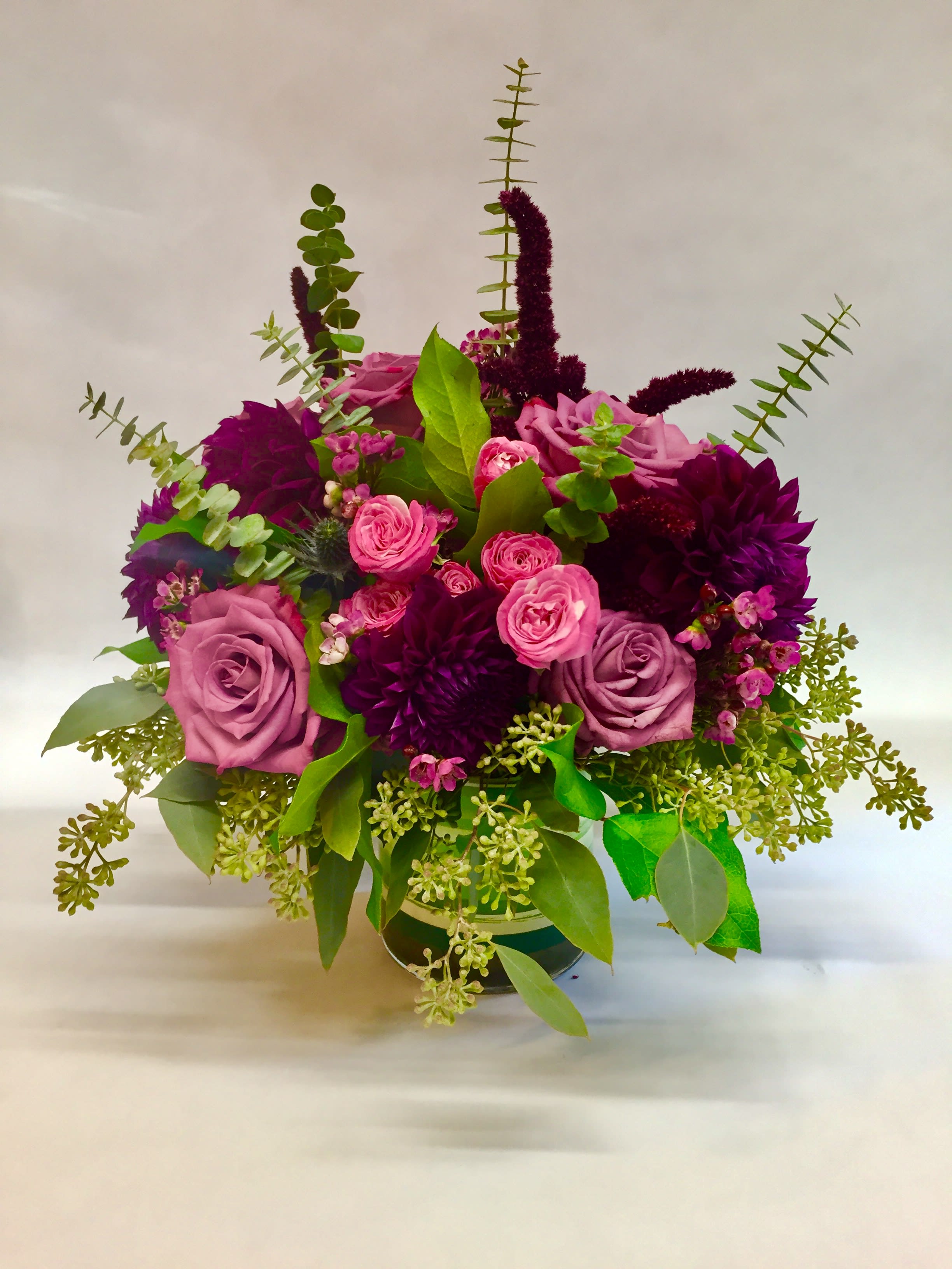 Bouquet of pink and purple roses with greenery in a vase