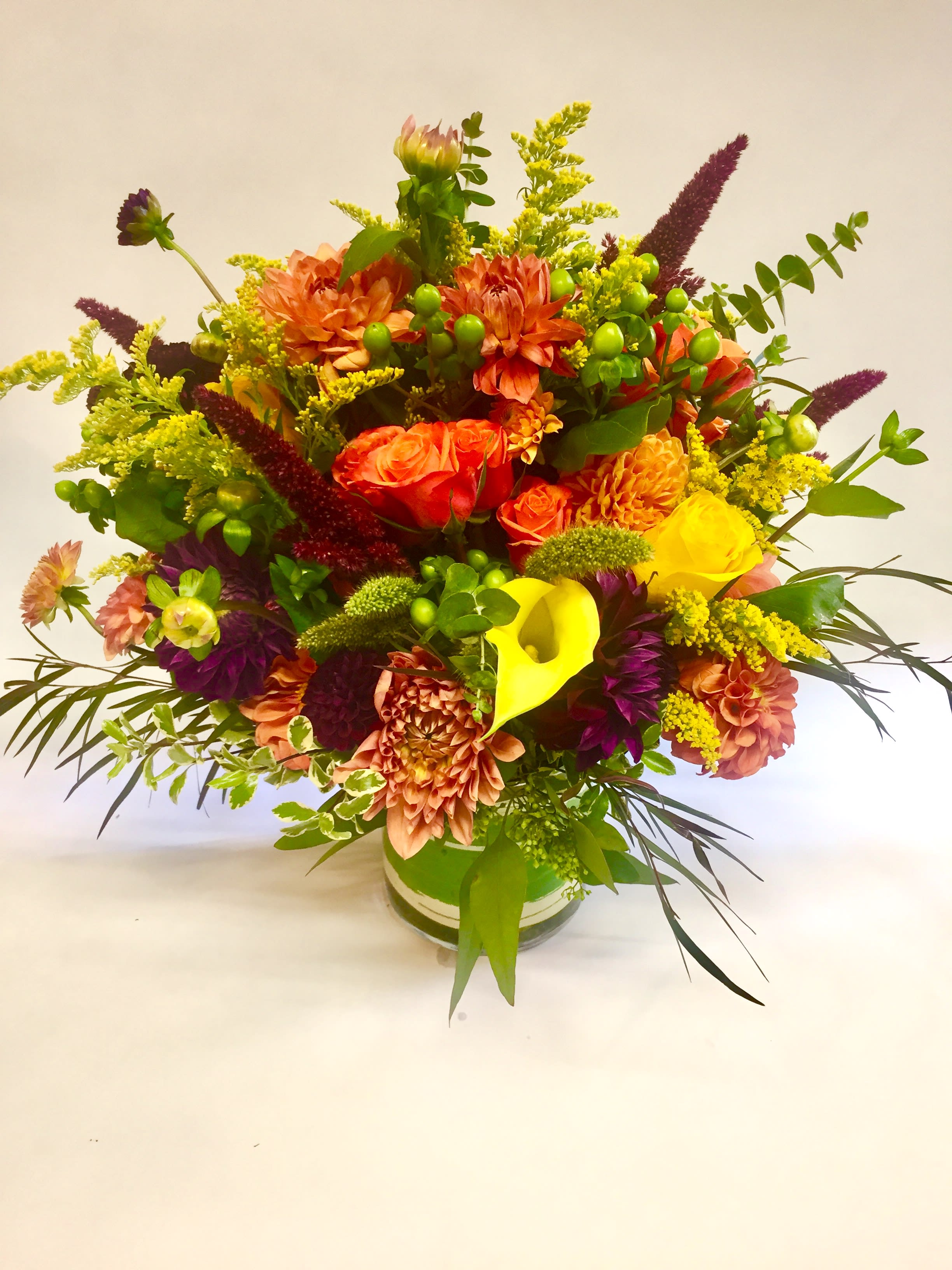 Bright mixed bouquet in a glass vase with orange, yellow, and purple flowers
