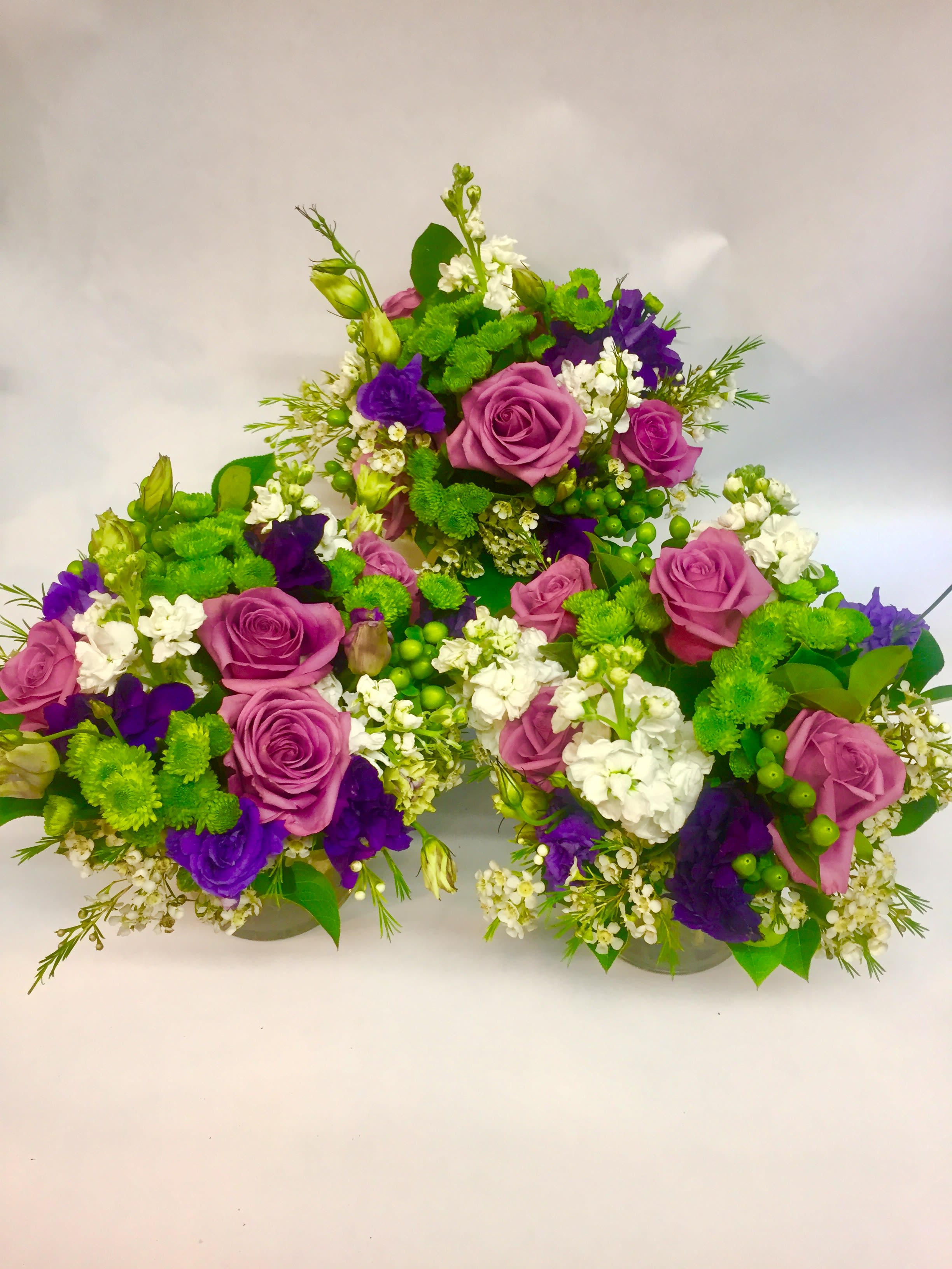 Purple roses and white flowers arranged in a low cluster