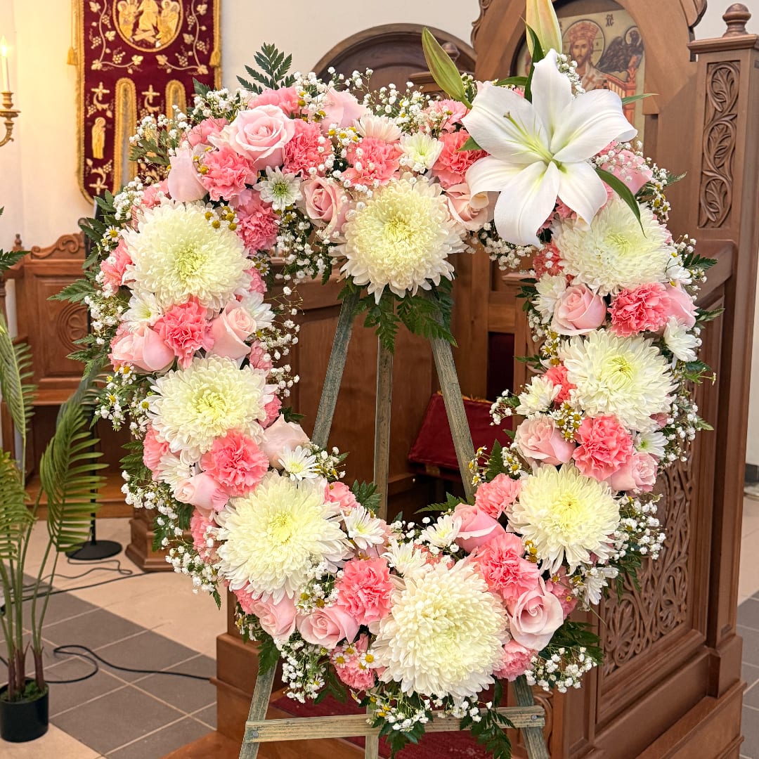Heart-shaped floral wreath with pink and white flowers on an easel