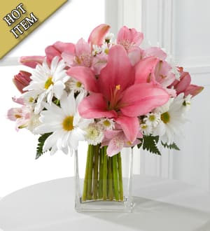 Pink lilies and white daisies arranged in a clear glass vase