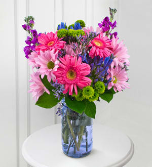 Colorful bouquet of daisies and mixed blooms in a blue glass vase