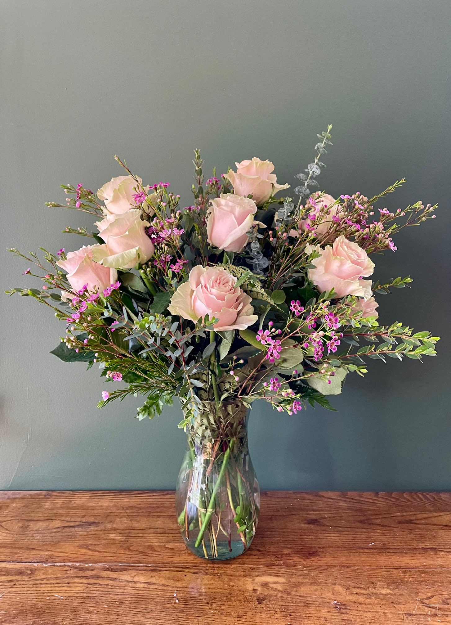 Dozen Pink Roses - This classic arrangement features a dozen light pink roses accented with fresh greenery for a soft, elegant look. Pink roses symbolize grace, admiration, and love, making this bouquet a popular choice for romantic flowers, anniversary roses, birthday flowers, and everyday flower delivery. Featuring: - Ecuadorian Roses - Styled with premium seasonal foliage Presentation Options: Tall clear vase measuring approximately 9". Vase included in price. Every order includes: A custom message card - simply enter your message at checkout and we'll take care of the rest.  As a local florist in Charleston South Carolina, everything is made fresh by us at our flower shop Downtown Charleston.