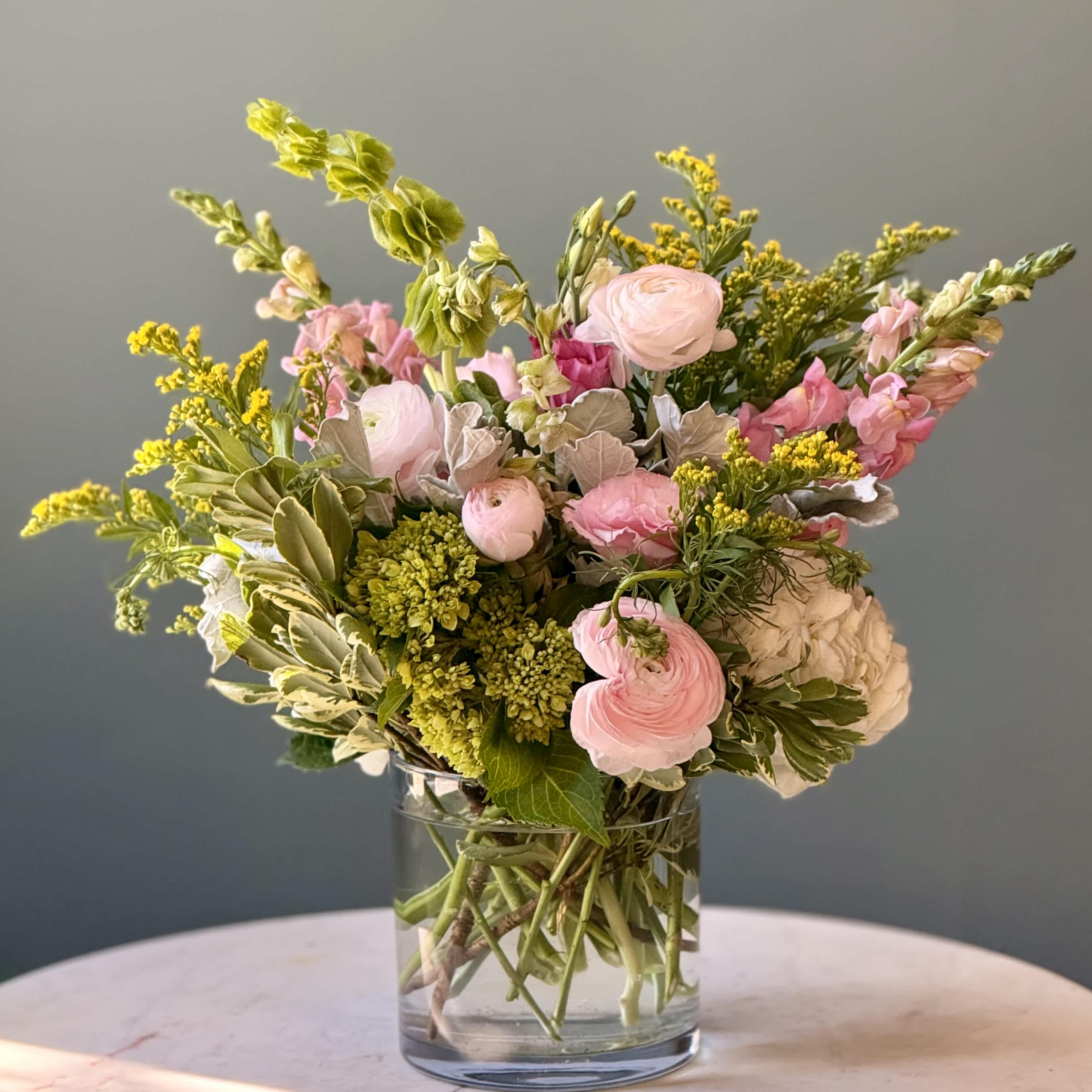 Pink and white flowers arranged in a clear glass vase