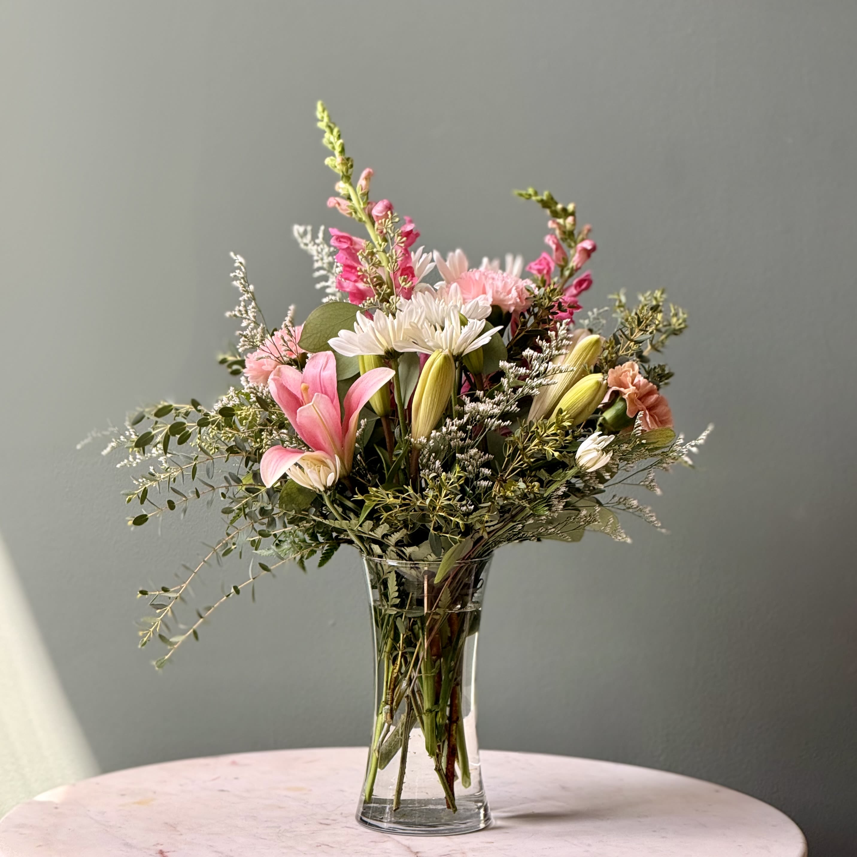 Lovely lily bouquet - Lilies, alstromerias and daisies in a vase arrangement. Color palette may vary depending on availability. As a local florist in Charleston South Carolina, everything is made fresh by us here at our flower shop Downtown Charleston.