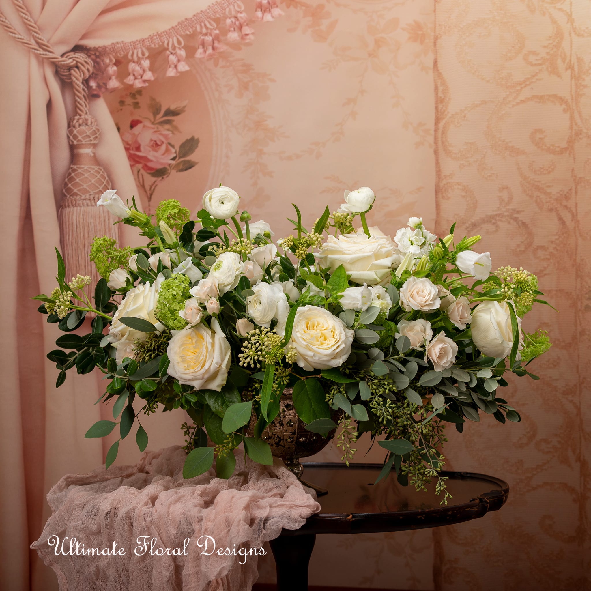 White and blush rose arrangement in a decorative urn