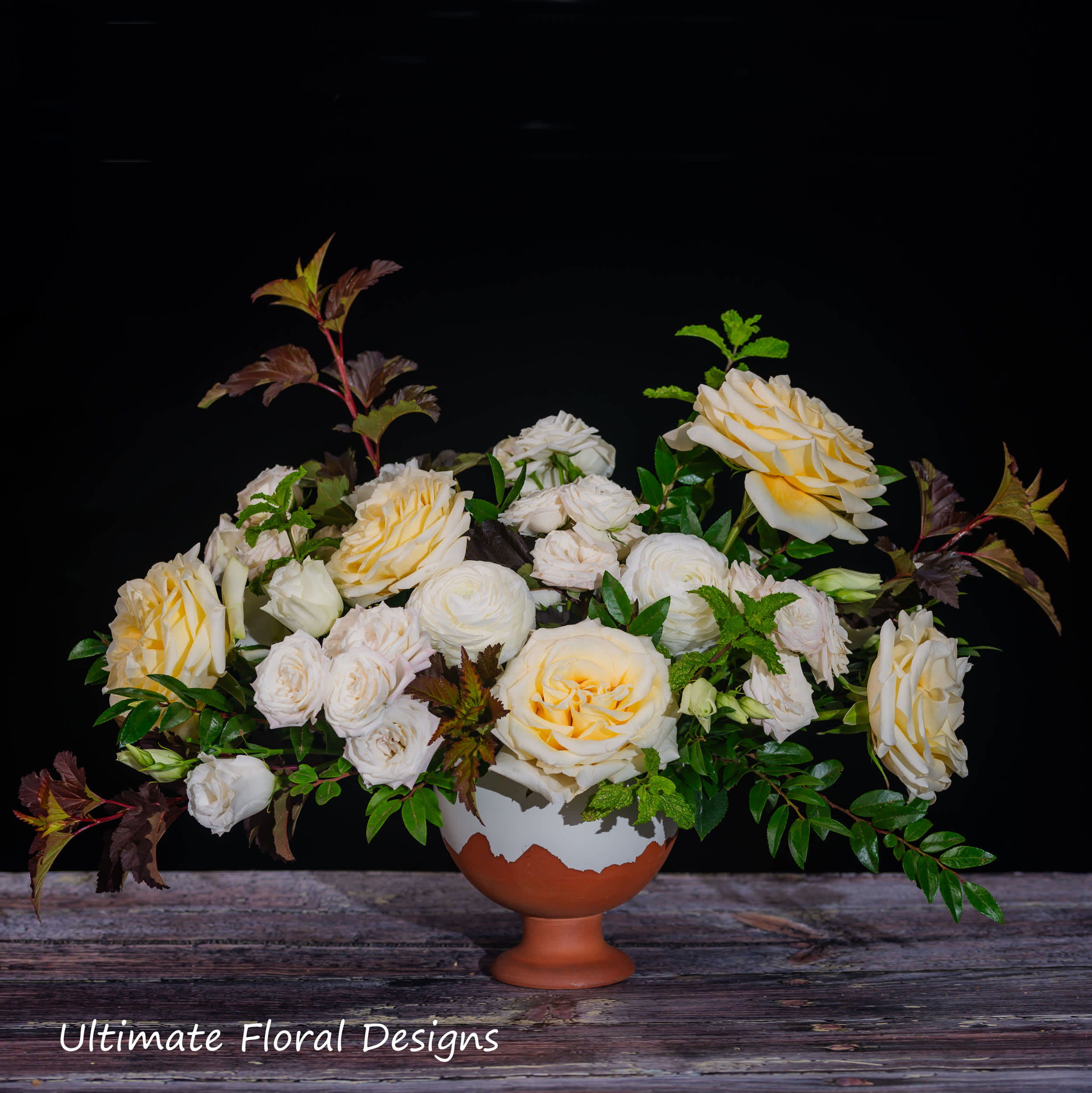 Cream and pale yellow roses arranged in a terracotta pedestal vase