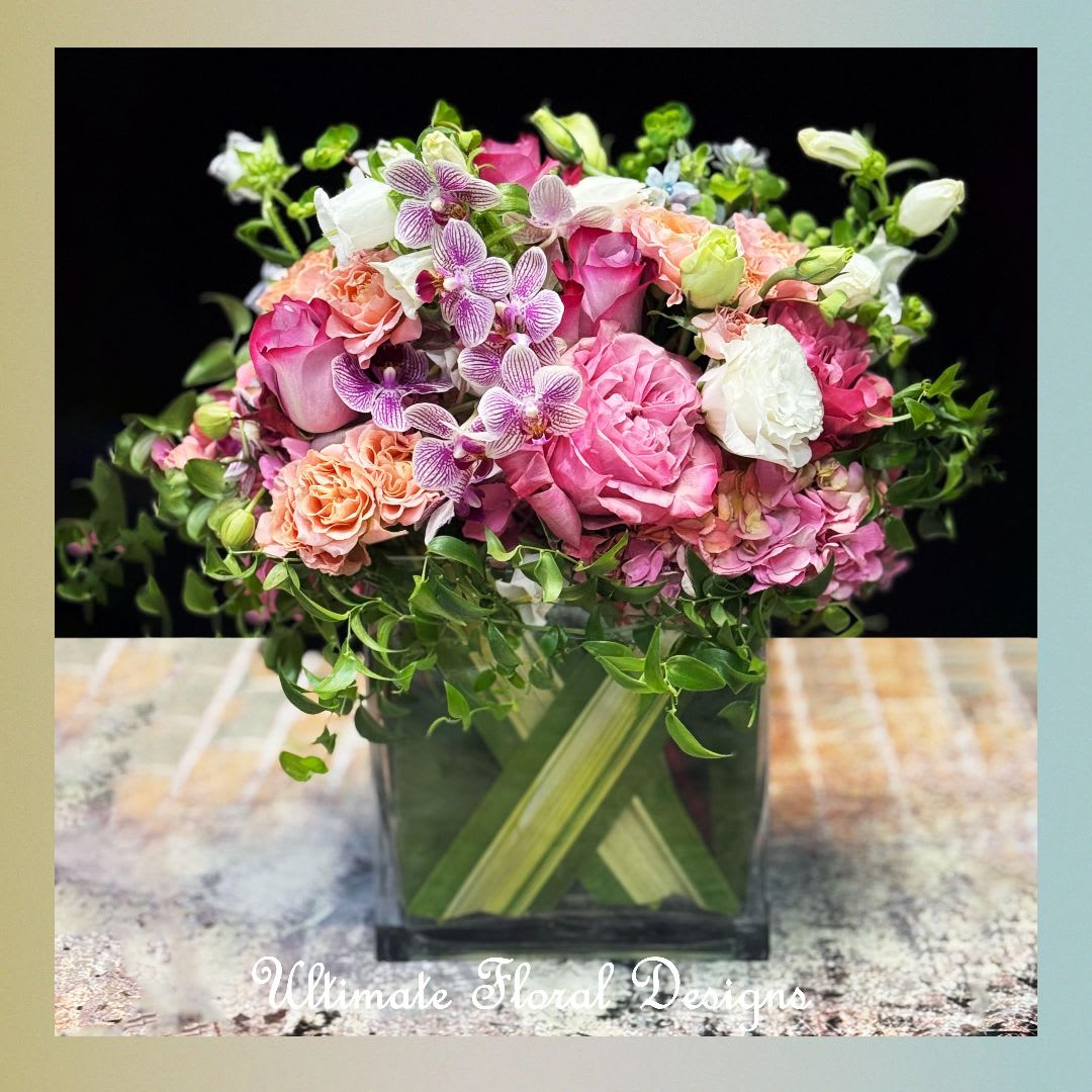Pink and white floral arrangement in a square glass vase