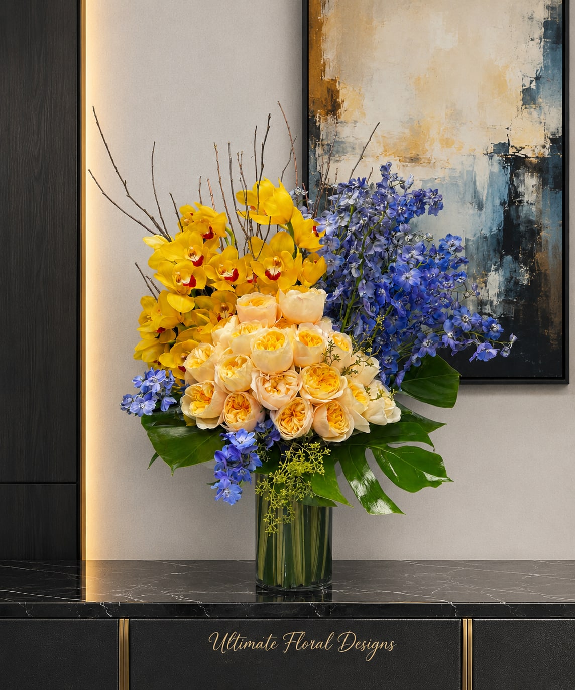 Yellow and peach roses with blue flowers in a glass vase