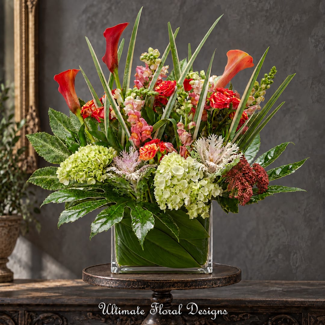 Tropical floral arrangement in a square glass vase with red calla lilies and hydrangeas