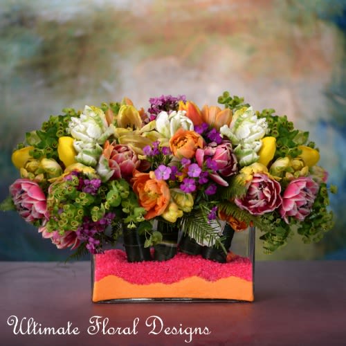 Colorful mixed bouquet in a rectangular glass vase with bright filler
