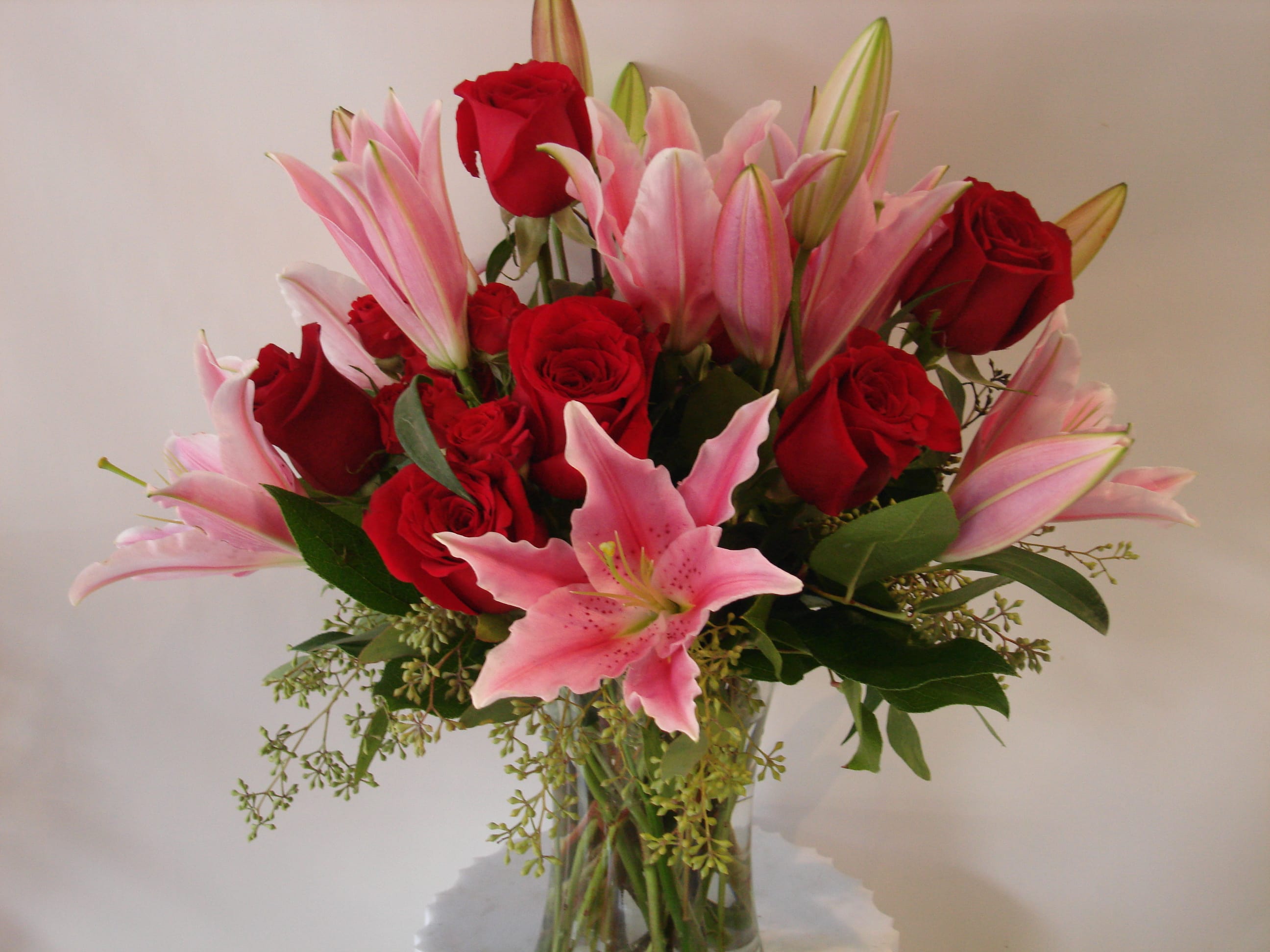 Bouquet of red roses and pink lilies in a clear glass vase